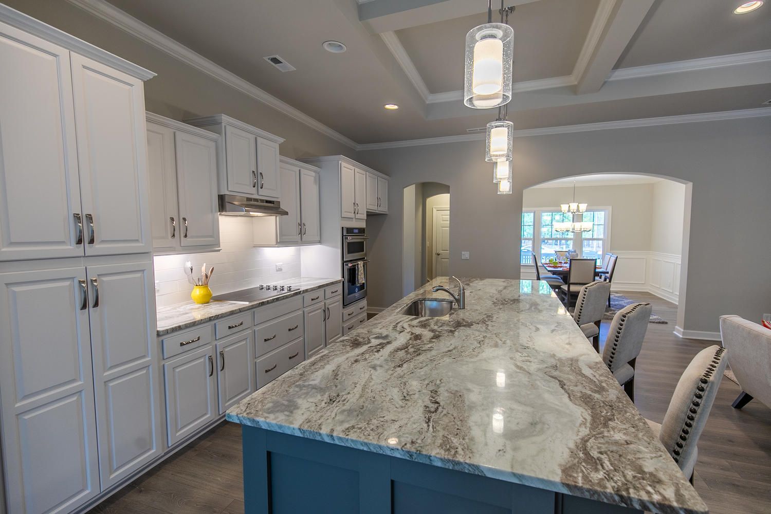 A kitchen with white cabinets , granite counter tops , and a large island.