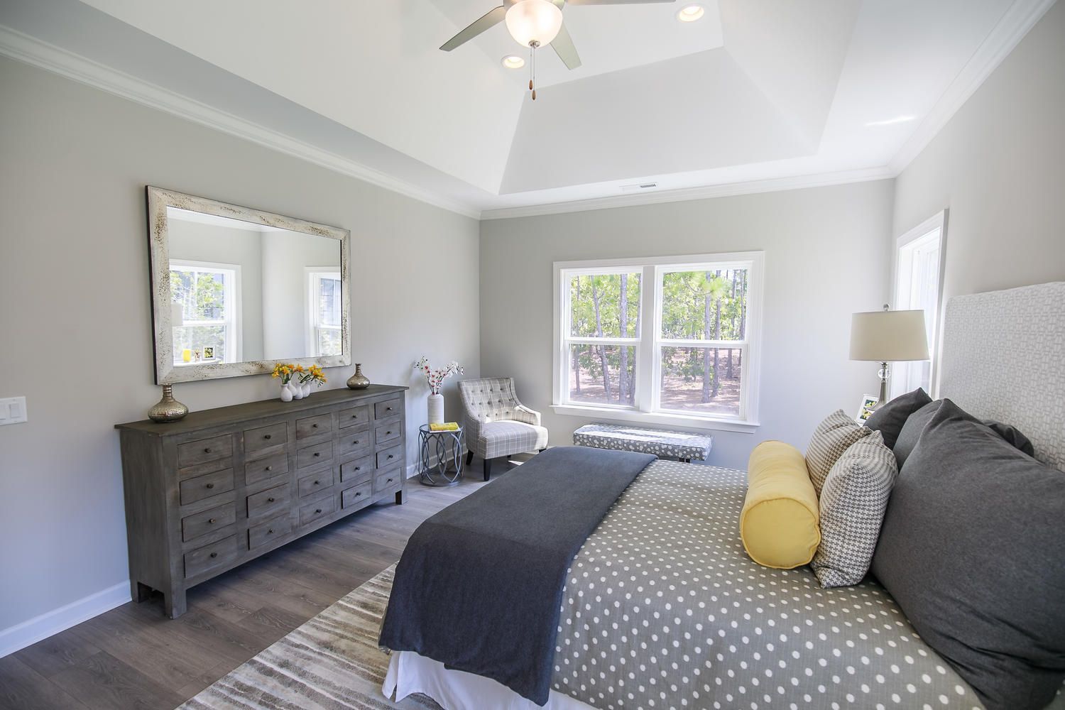 A bedroom with a bed , dresser , mirror and ceiling fan.