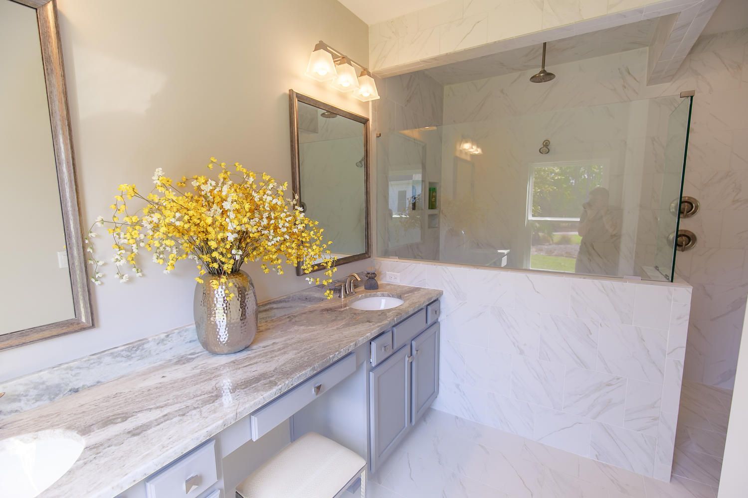 A bathroom with two sinks , a mirror , and a walk in shower.