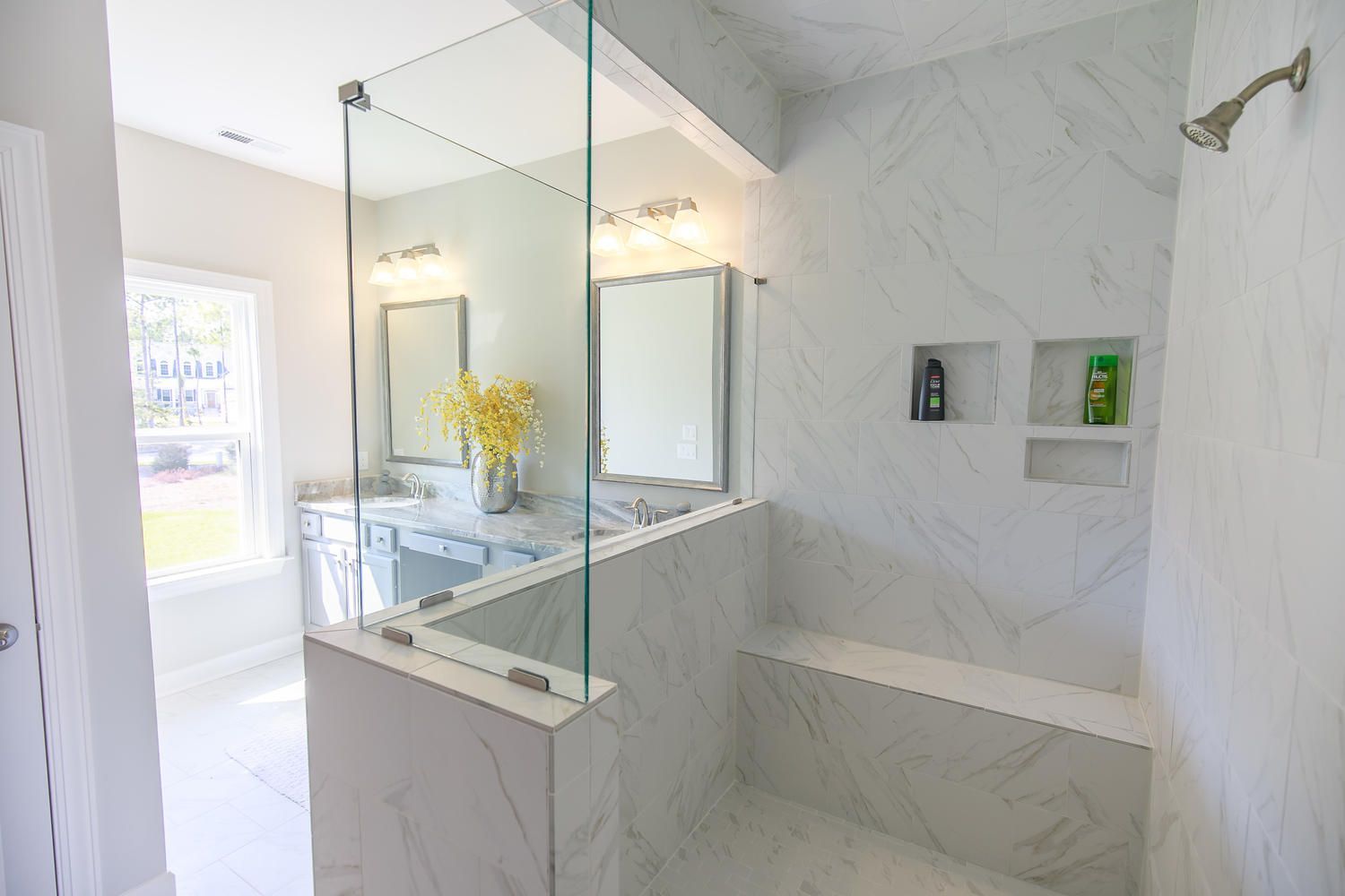 A bathroom with a walk in shower , sink and mirror.