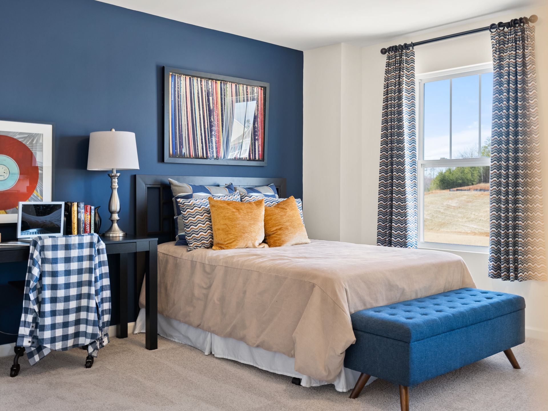 A bedroom with blue walls , a bed , a desk and a bench.