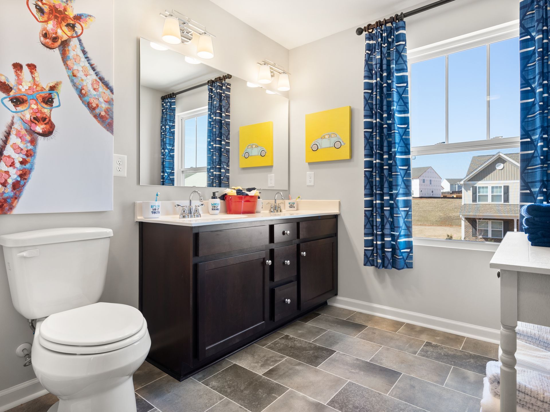 A bathroom with a toilet , sink , mirror and window.