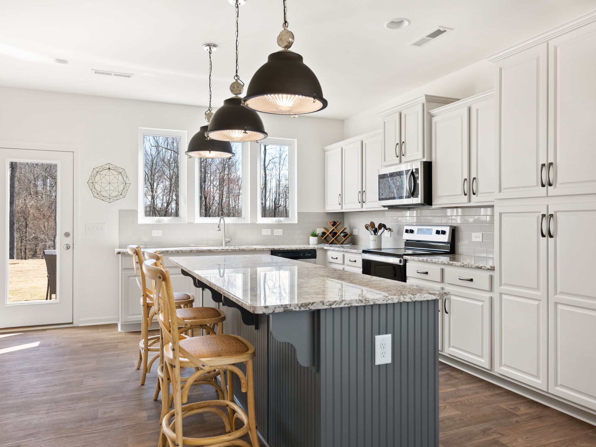 A kitchen with white cabinets , granite counter tops , a large island and stools.