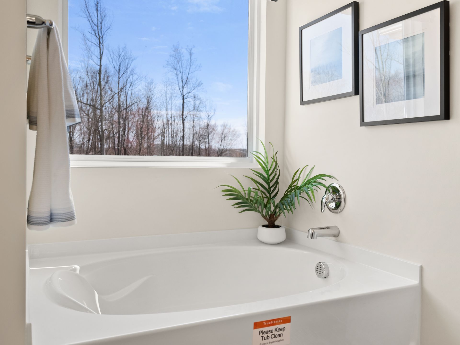 A bathroom with a tub and a window with trees in the background.