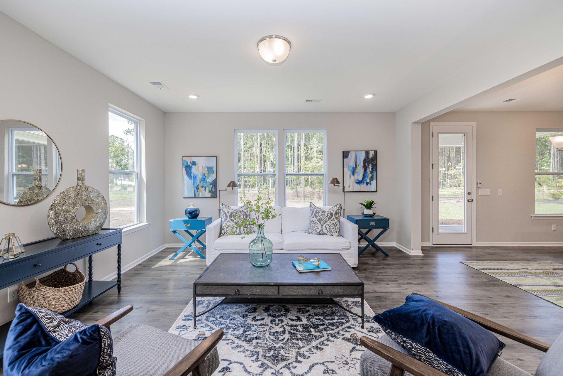 A living room with a couch , chairs , a coffee table and a mirror.