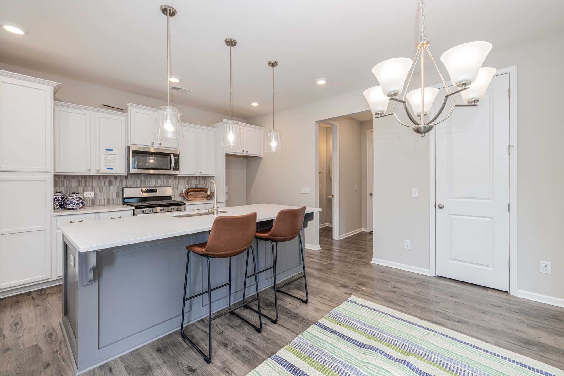 A kitchen with a large island , stools , and a chandelier.