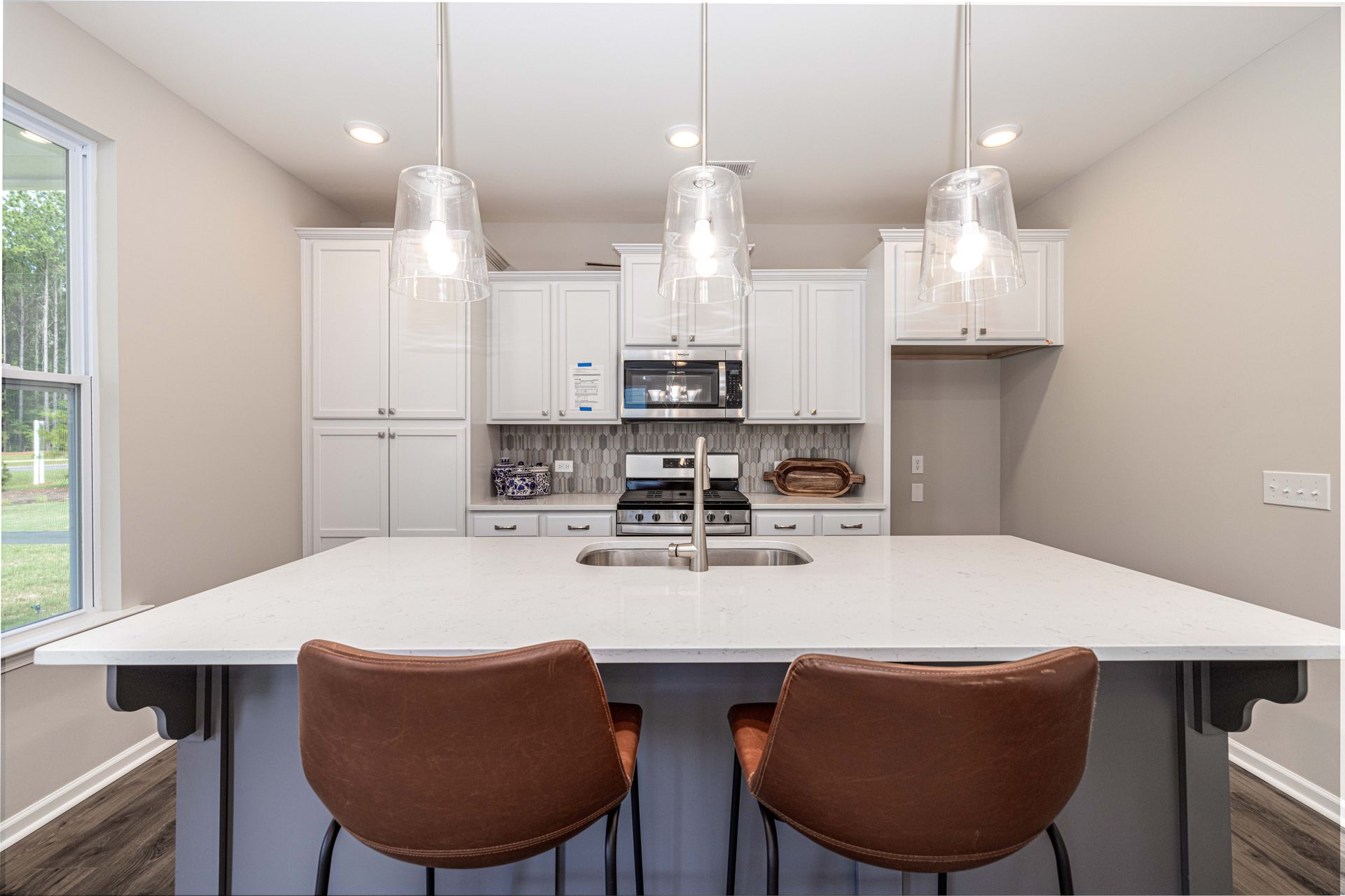 A kitchen with a large island and two chairs.