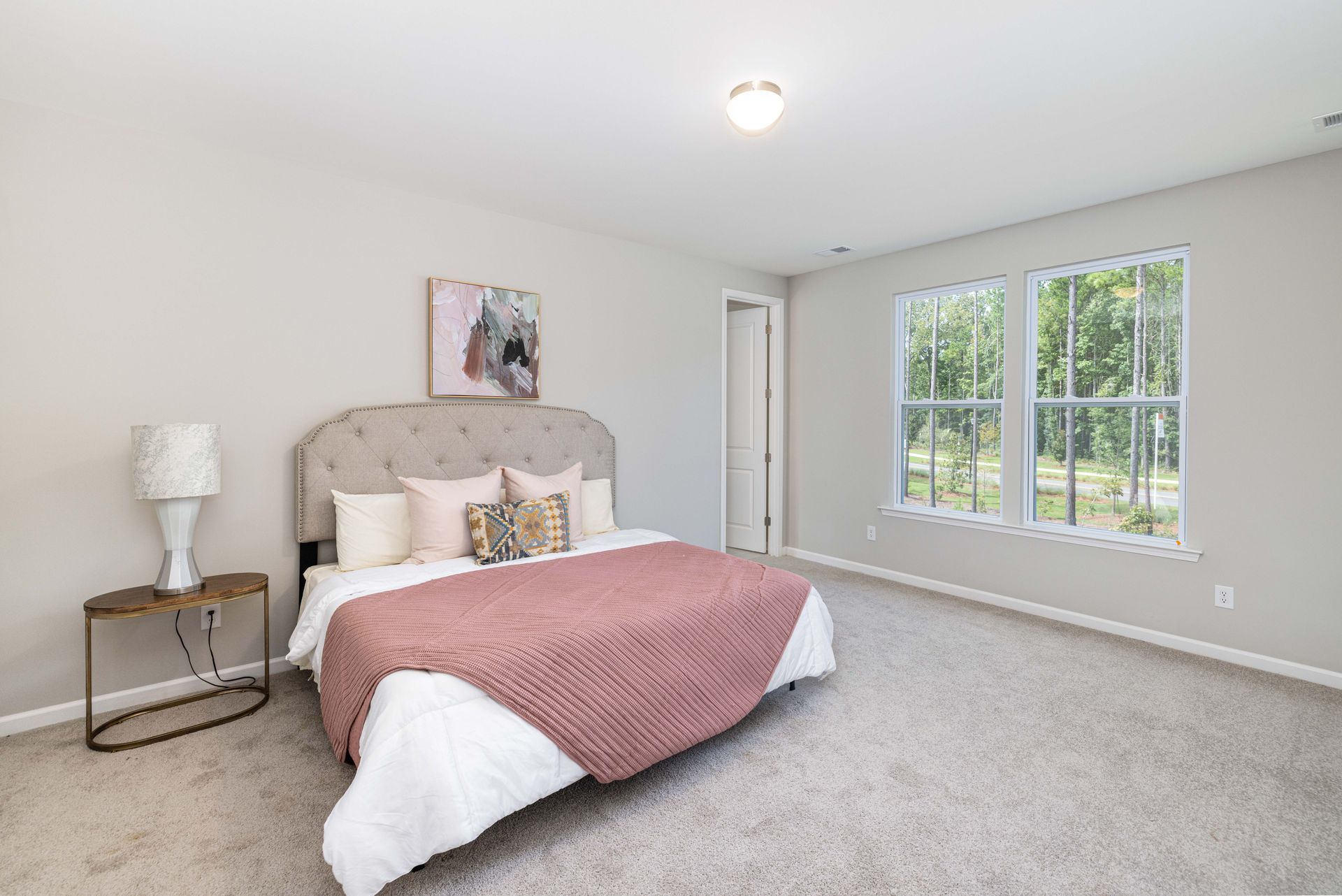 A bedroom with a large bed and two windows.