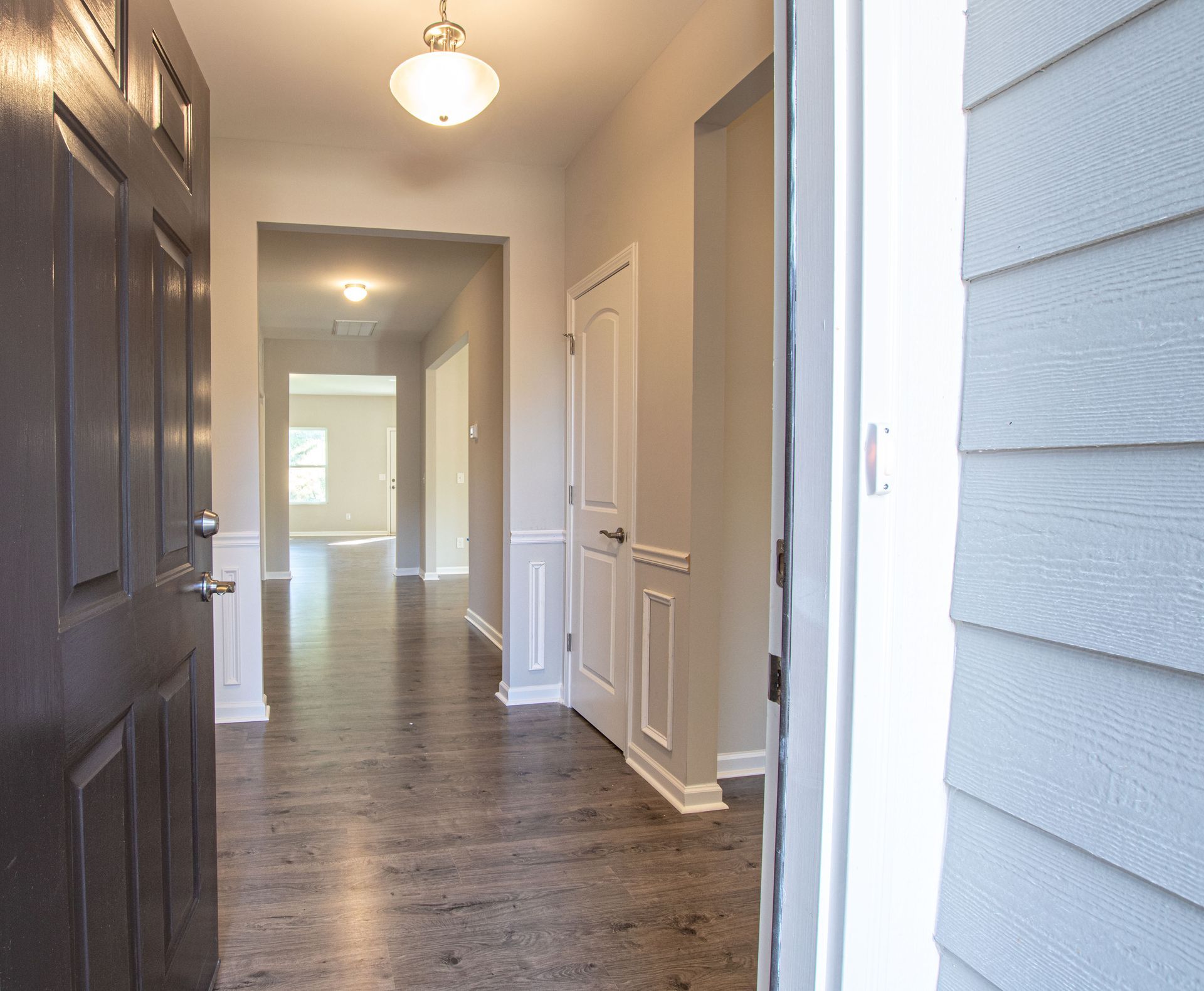 A hallway in a house with hardwood floors and a black door.