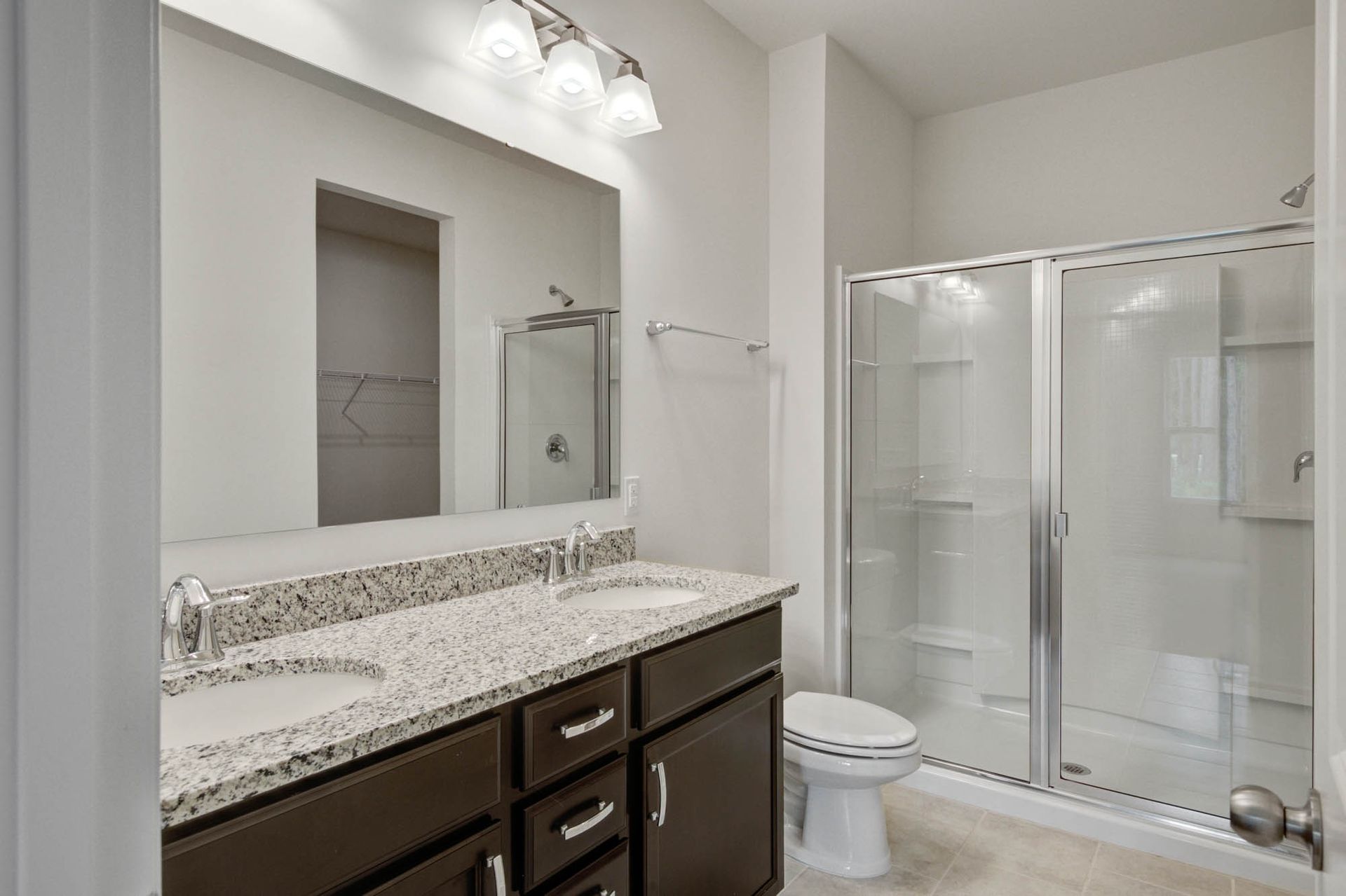 A bathroom with two sinks , a toilet , and a walk in shower.