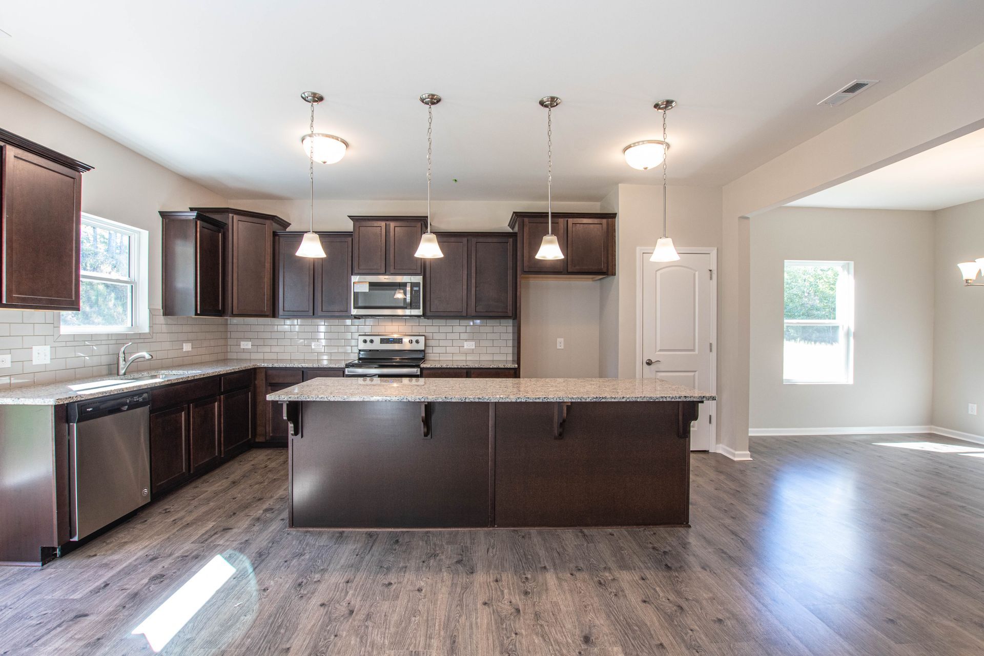 A kitchen in a new home with stainless steel appliances and a large island.