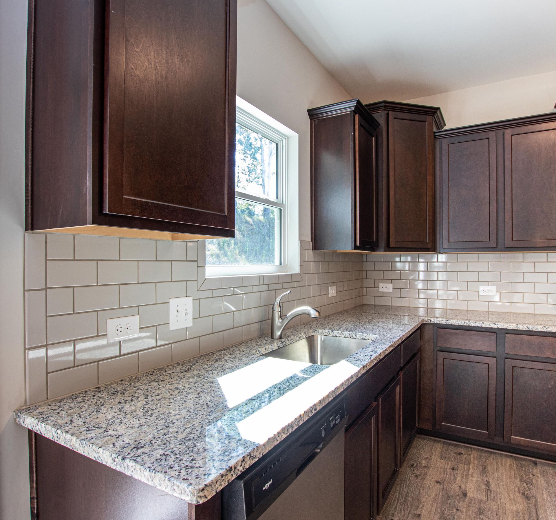 A kitchen with granite counter tops and dark cabinets