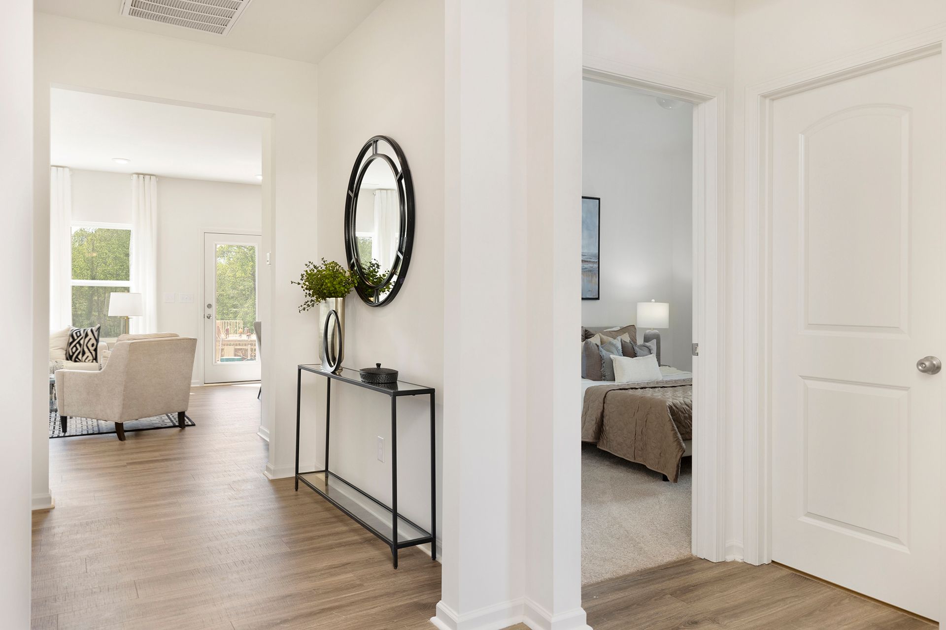 A hallway in a house with a mirror on the wall and a table.