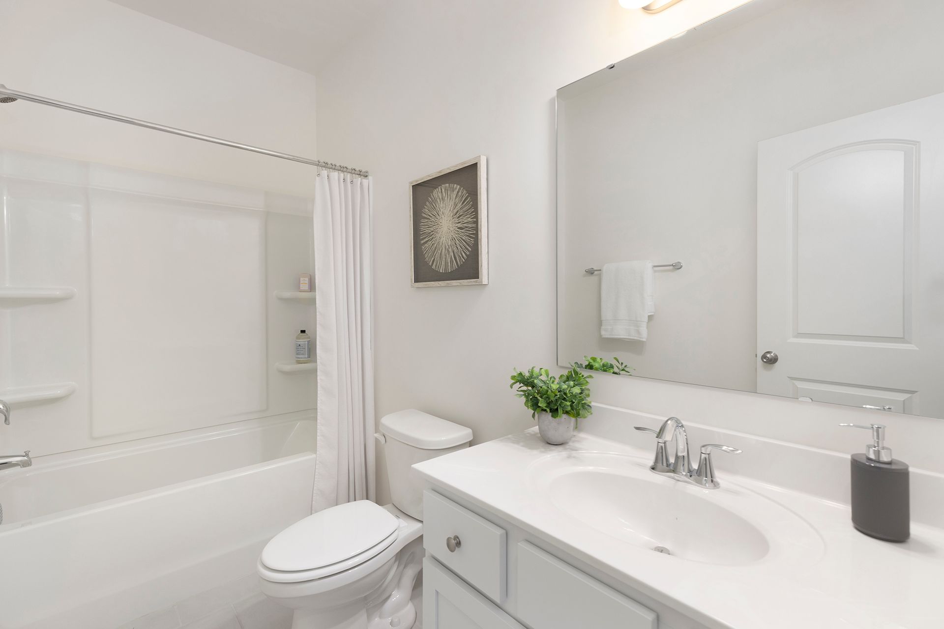 A bathroom with a toilet , sink , tub and mirror.