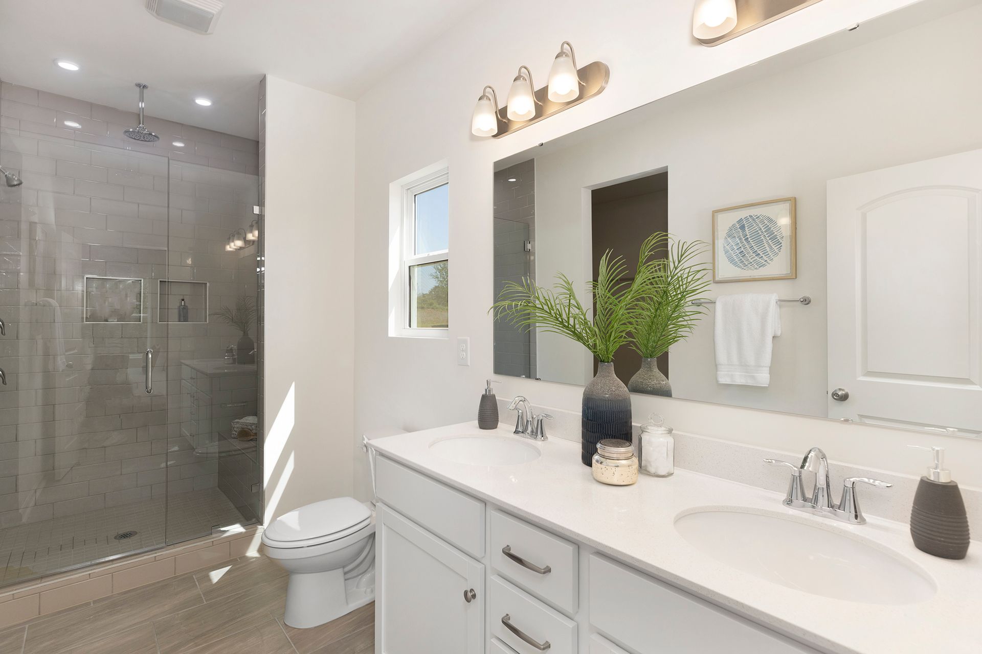 A bathroom with a toilet , sink , mirror and walk in shower.