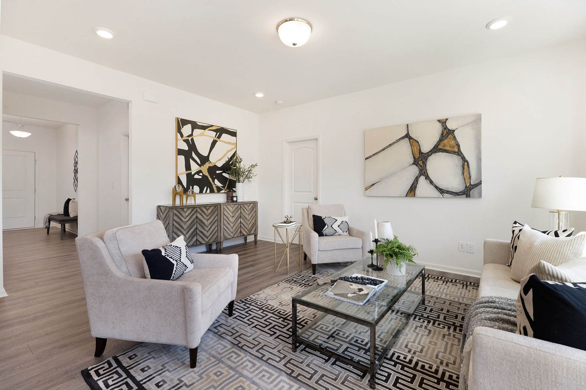 A living room with a couch , two chairs , a coffee table and a rug.