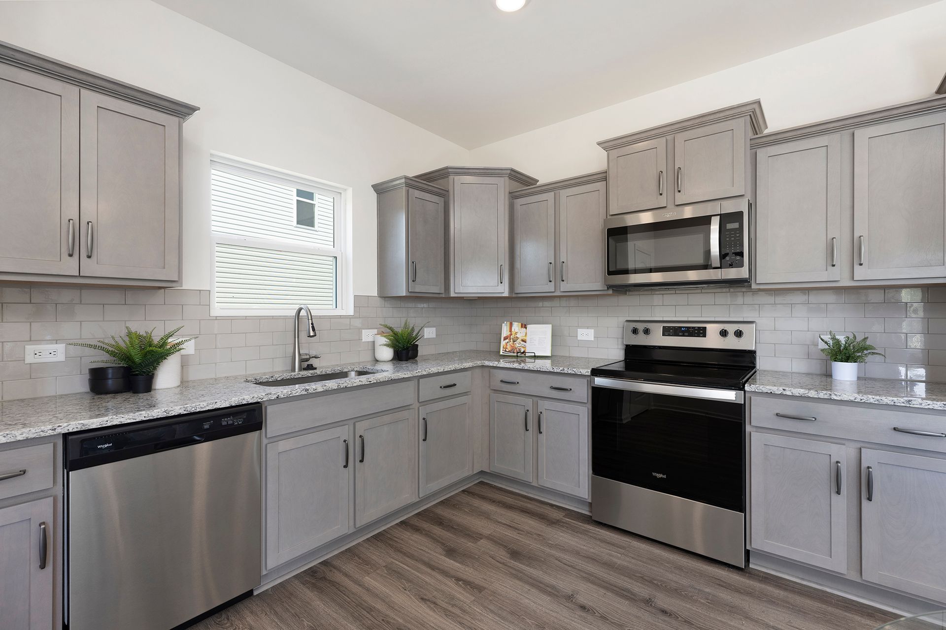 A kitchen with gray cabinets and stainless steel appliances.