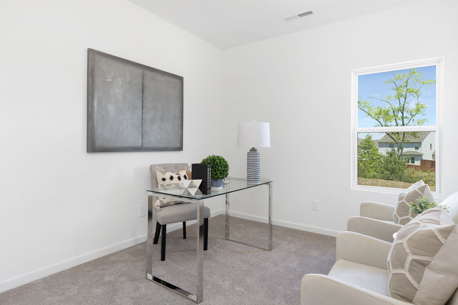 A room with a desk , chairs , and a window.