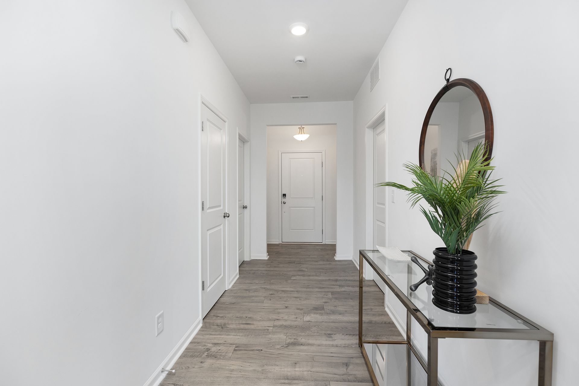 A long hallway with a table and a mirror.