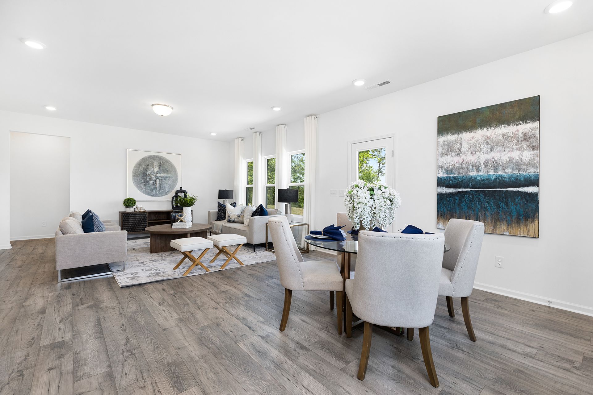 A living room with a dining table and chairs and a painting on the wall.