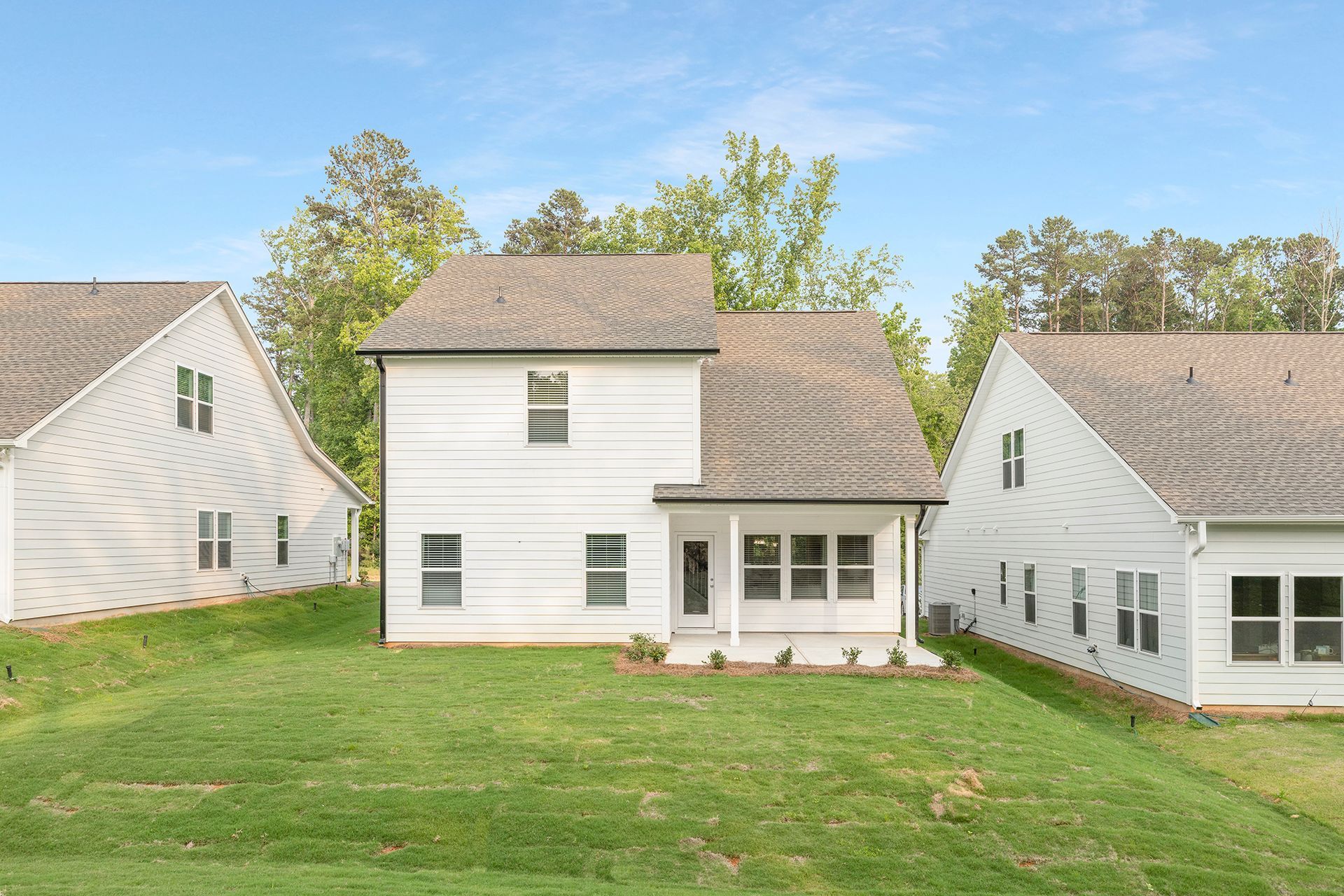 The back of a white house with a large lawn in front of it.