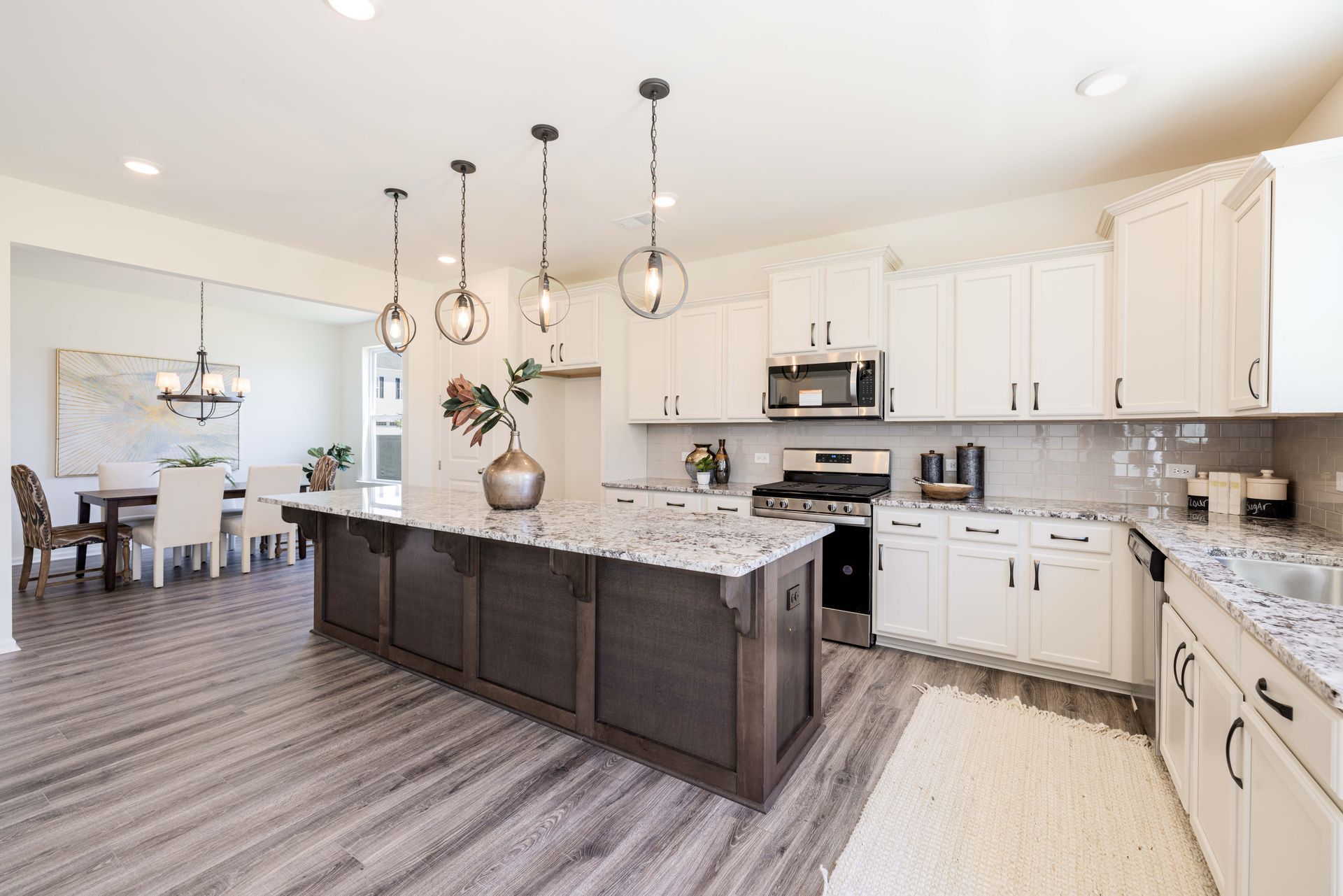 A kitchen with white cabinets , granite counter tops , stainless steel appliances and a large island.