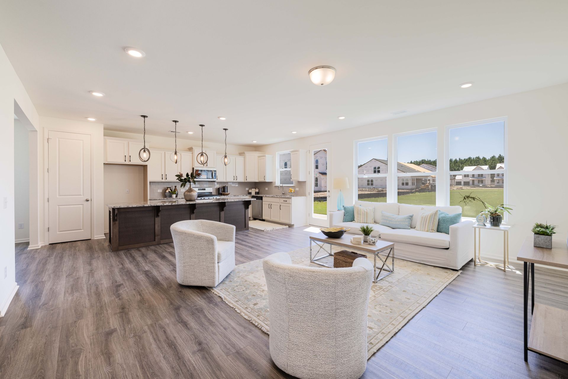 A living room with a couch , chairs , a coffee table and a kitchen.