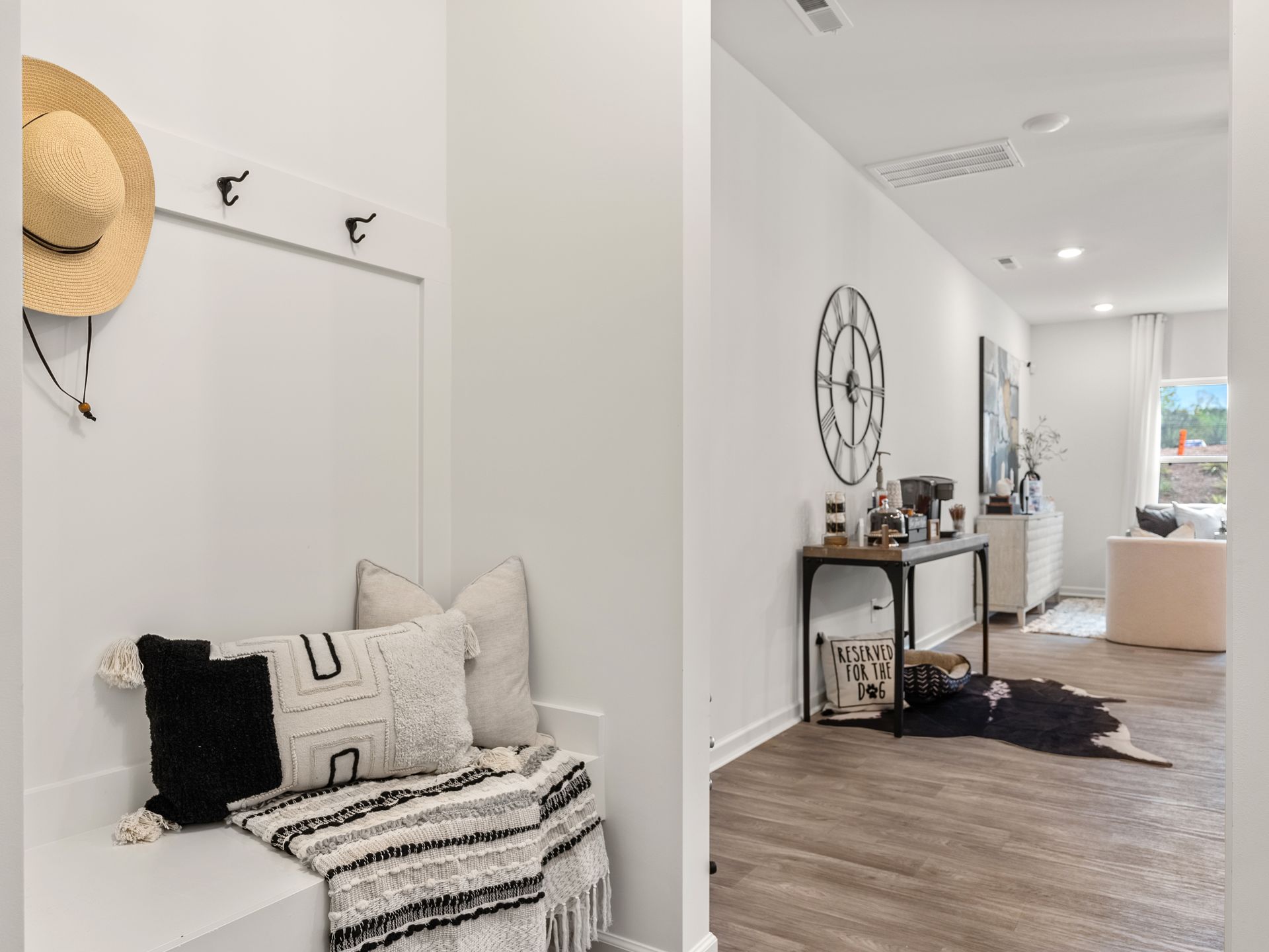 There is a bench in the hallway with a hat hanging on the wall.