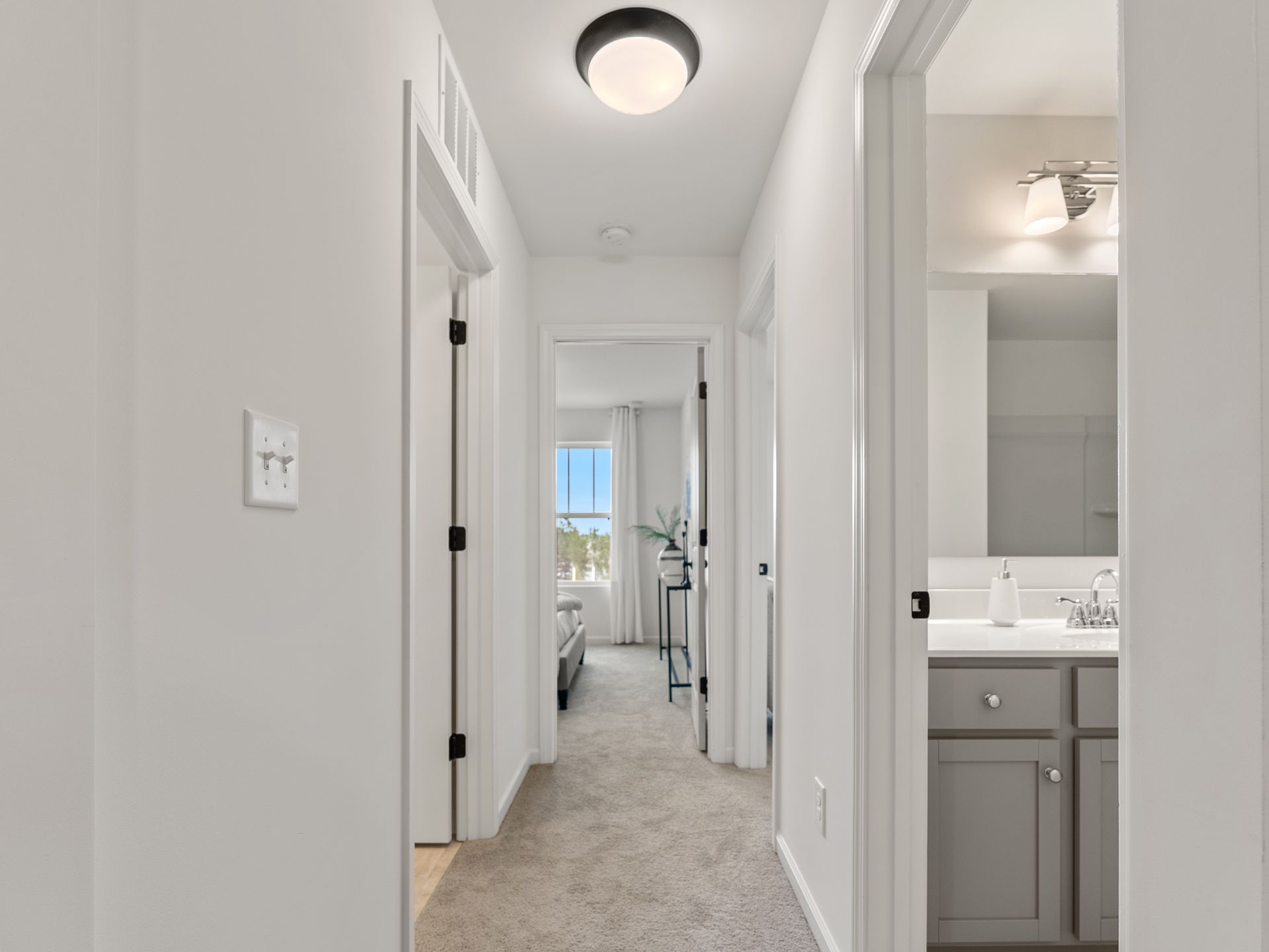 A hallway leading to a bedroom and bathroom in a house.
