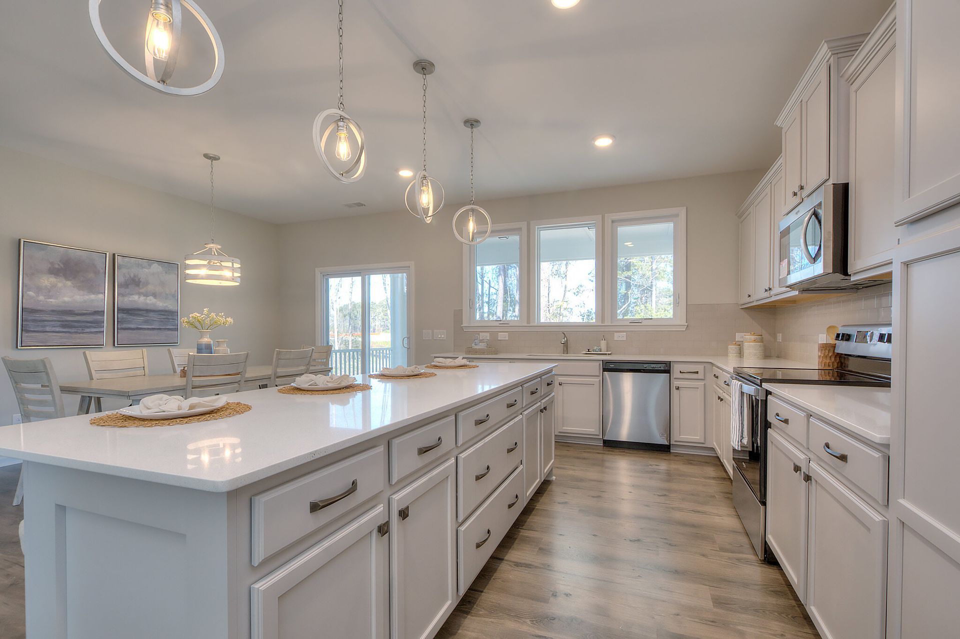 A kitchen with white cabinets , stainless steel appliances , and a large island.
