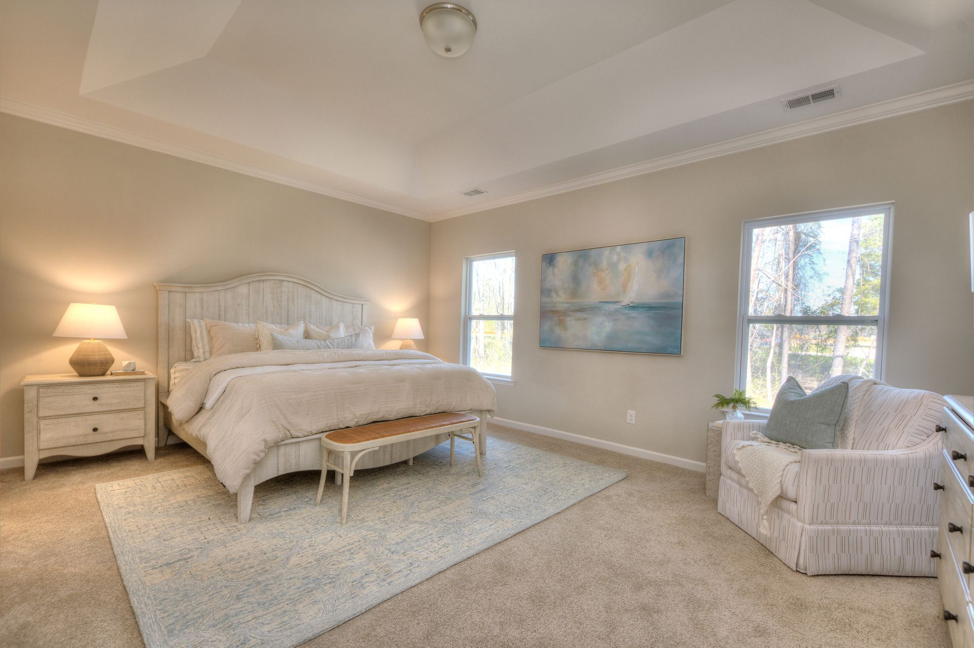 A bedroom with a king size bed , chair , dresser , nightstand and two windows.