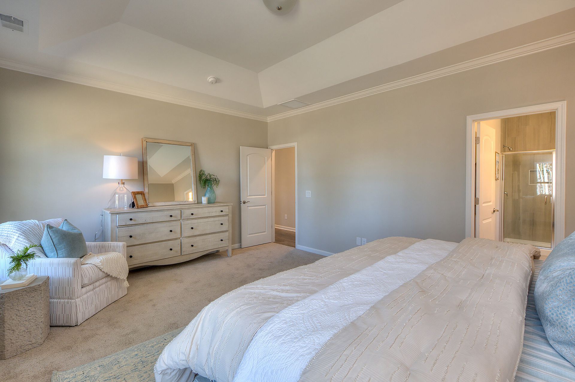 A bedroom with a bed , dresser , chair and mirror.