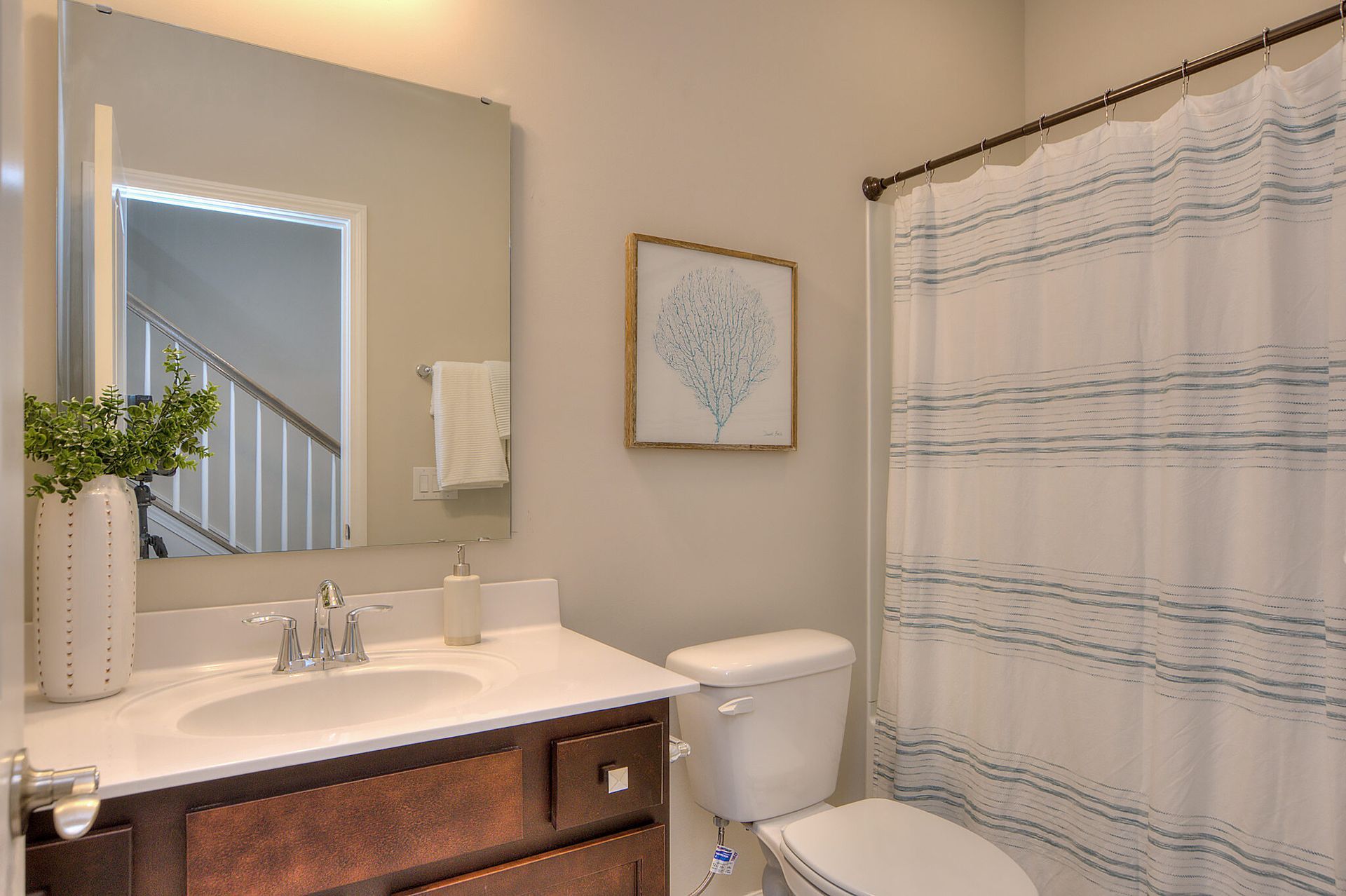 A bathroom with a sink , toilet , shower curtain and mirror.
