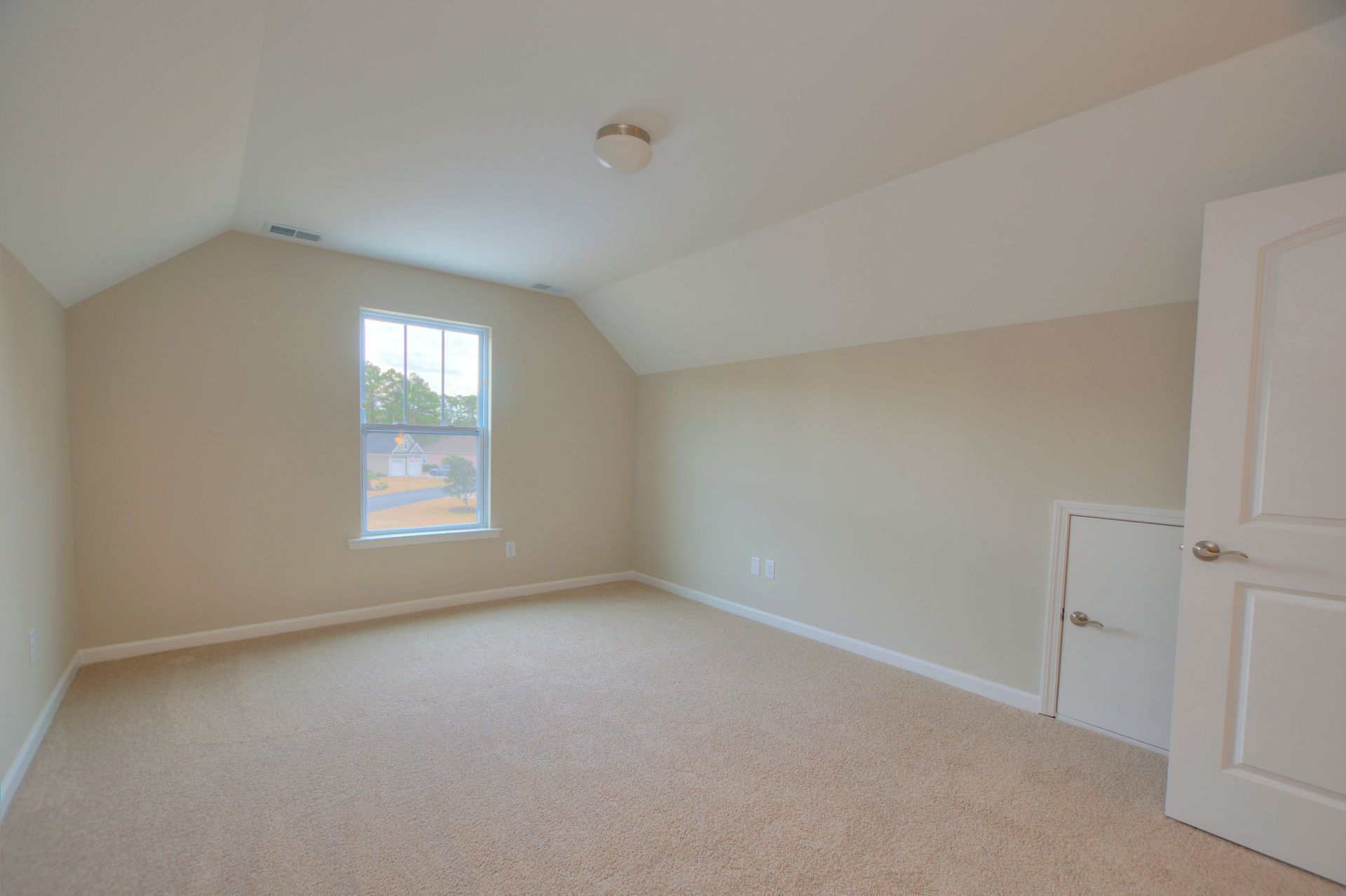 An empty bedroom with a window and a white door.