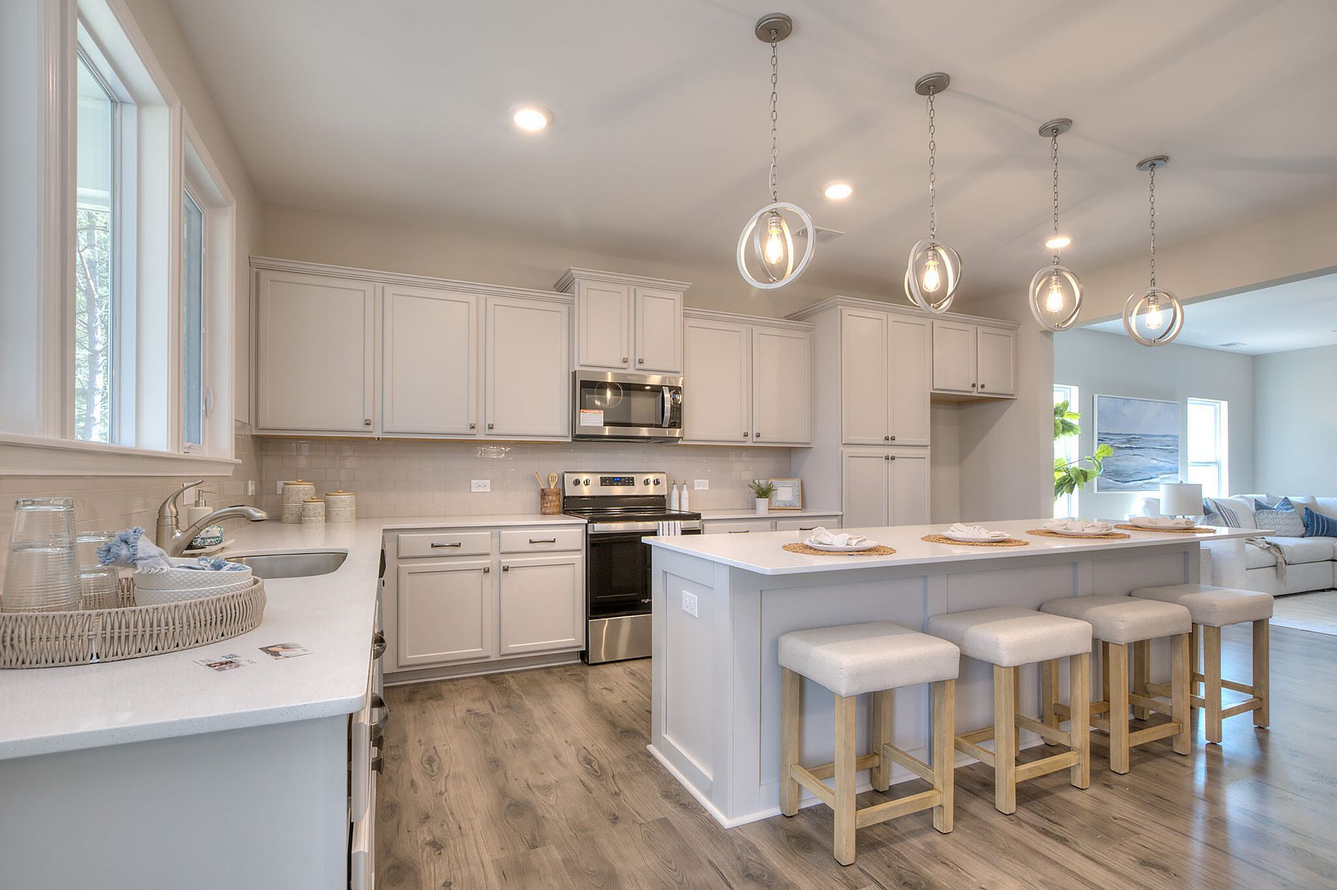 A kitchen with white cabinets , stainless steel appliances , and a large island.