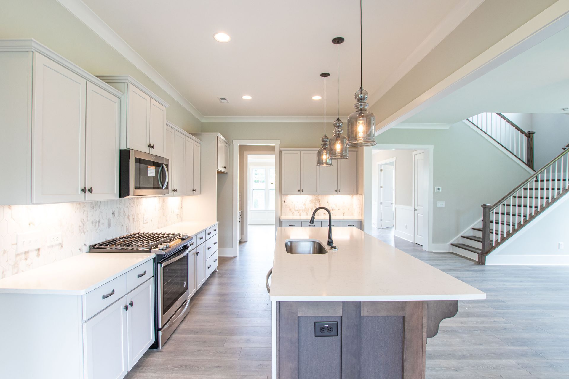 A kitchen with white cabinets , stainless steel appliances , and a large island.