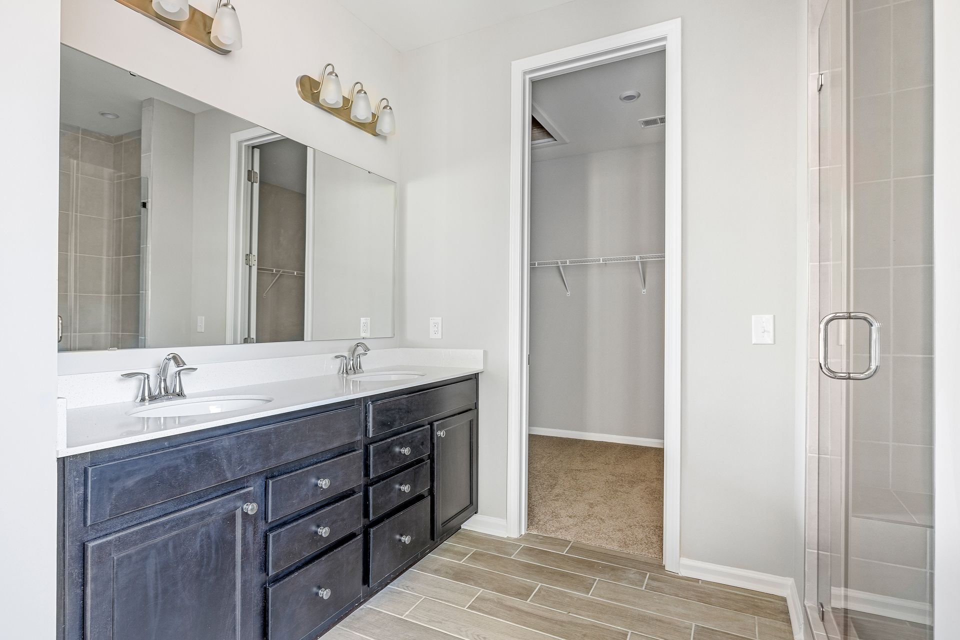 A bathroom with two sinks and a walk in closet.