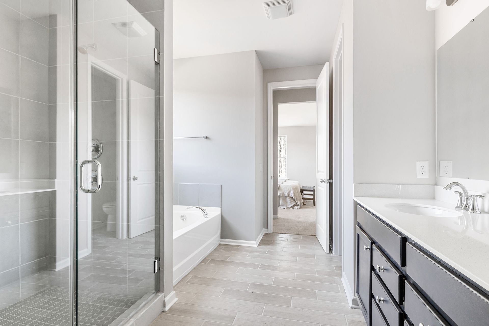 A bathroom with two sinks , a tub , and a walk in shower.