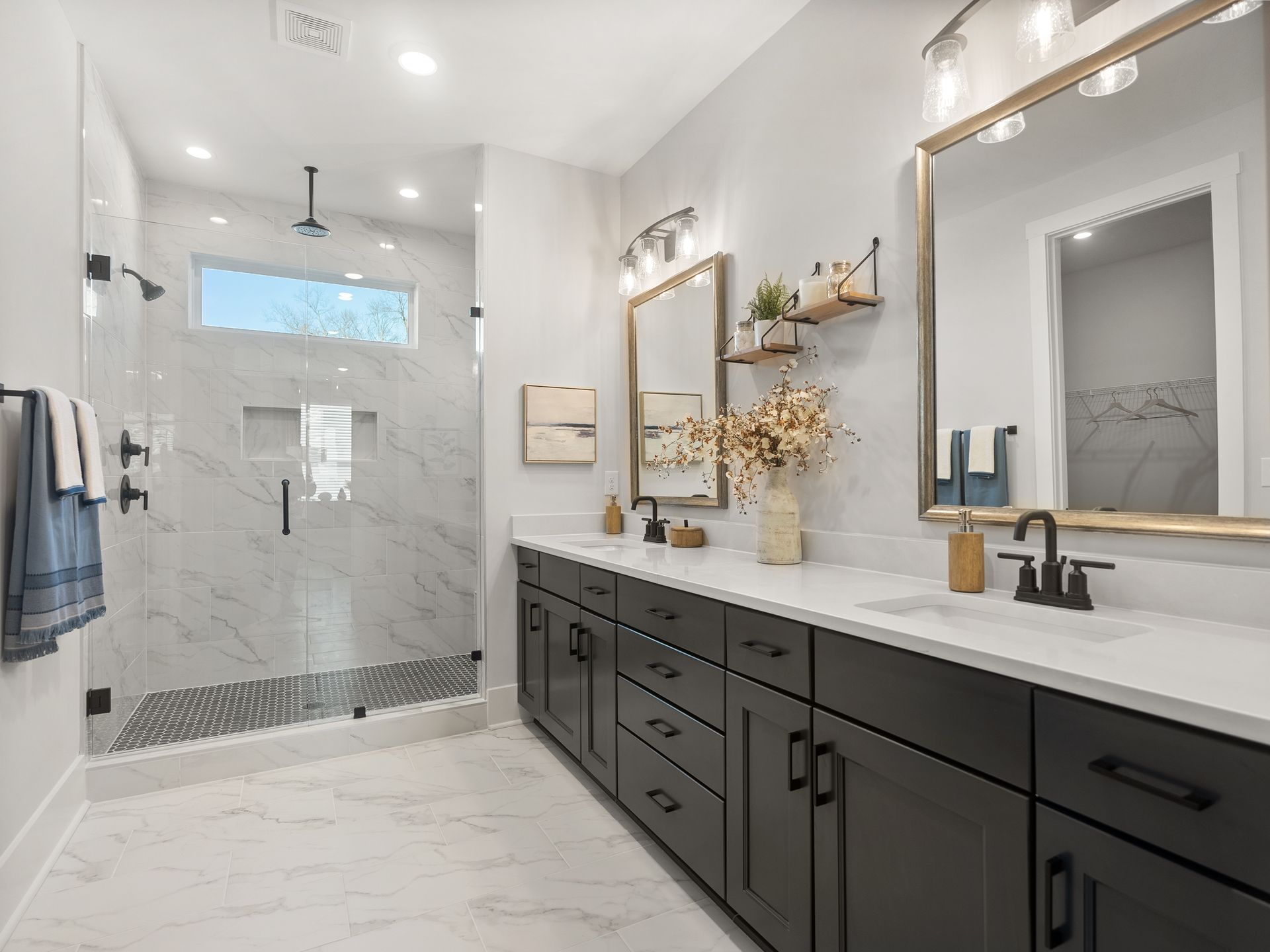 a bathroom with two sinks , two mirrors and a walk in shower .