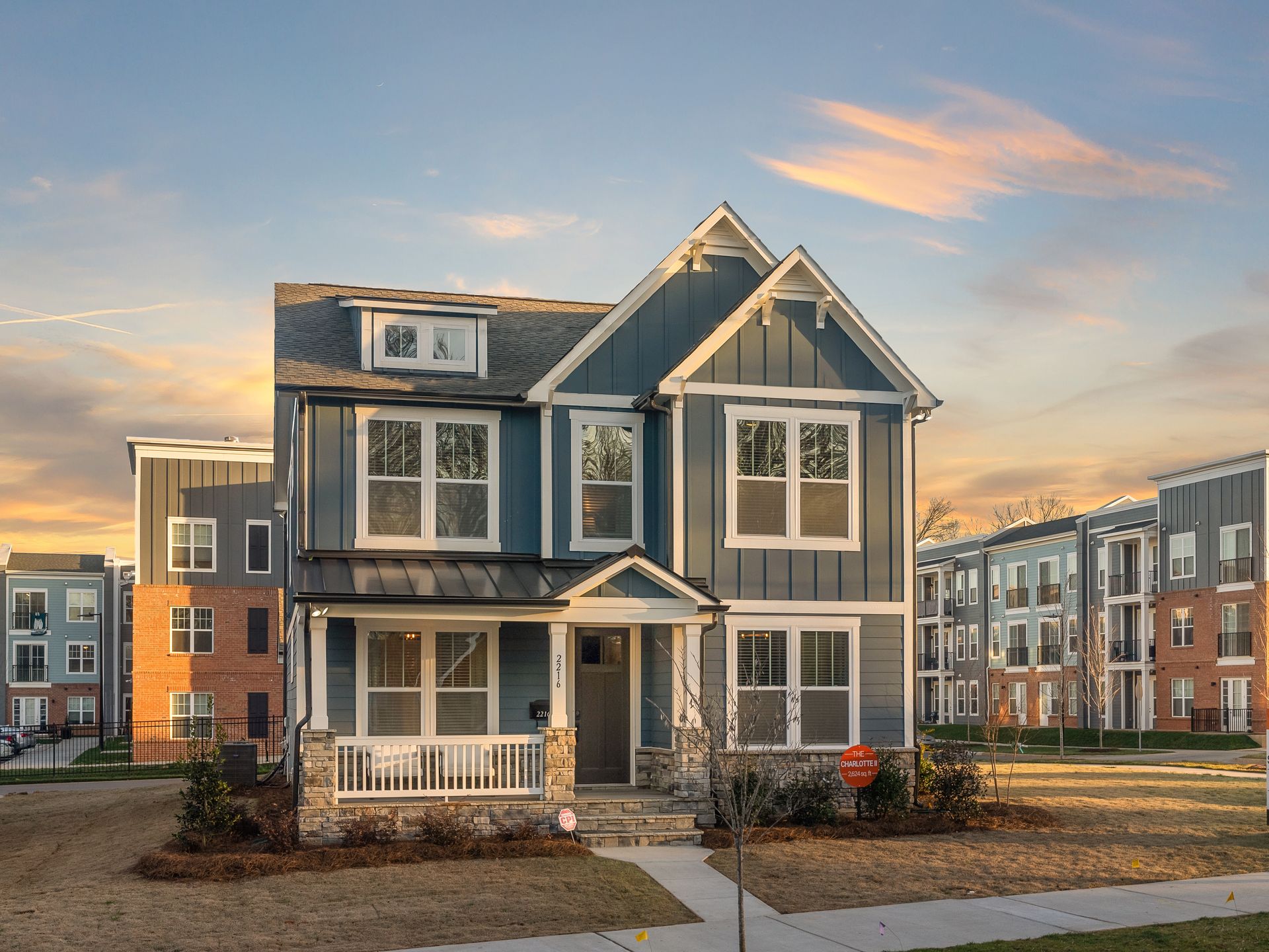 A blue house with a white porch is sitting in front of a building.