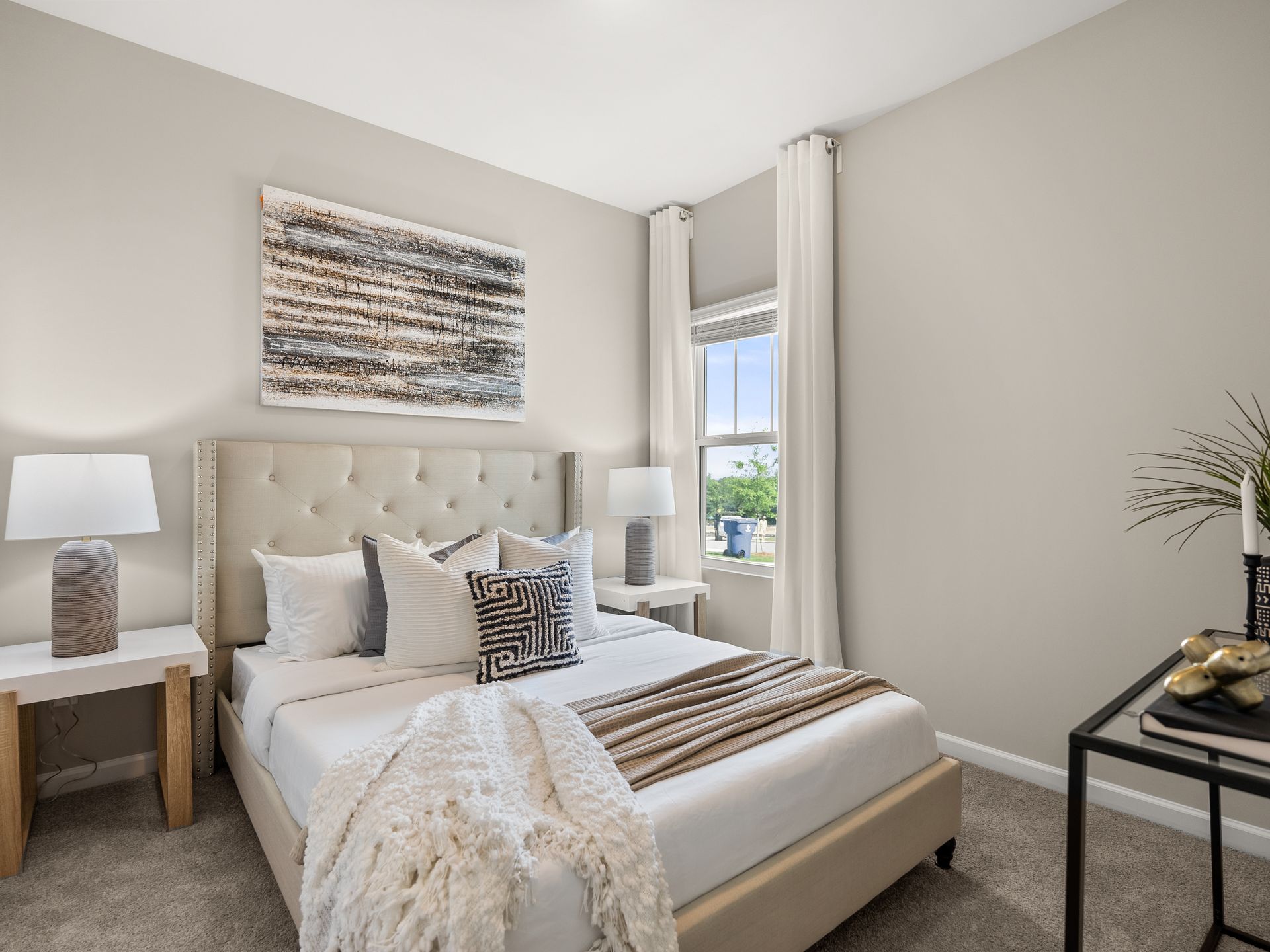 A bedroom with a bed , lamps , nightstands and a window.