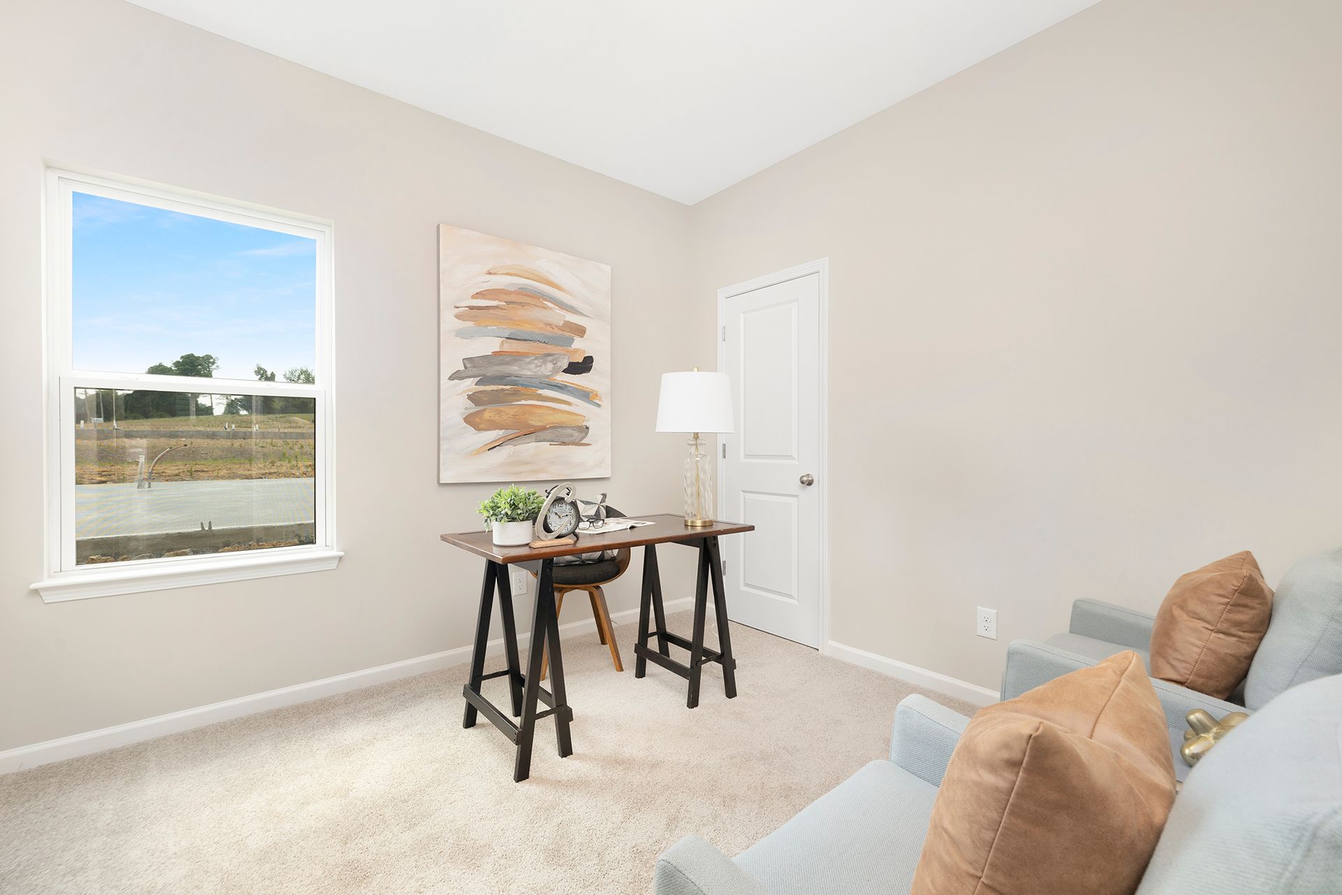 A living room with a desk , couch , and window.