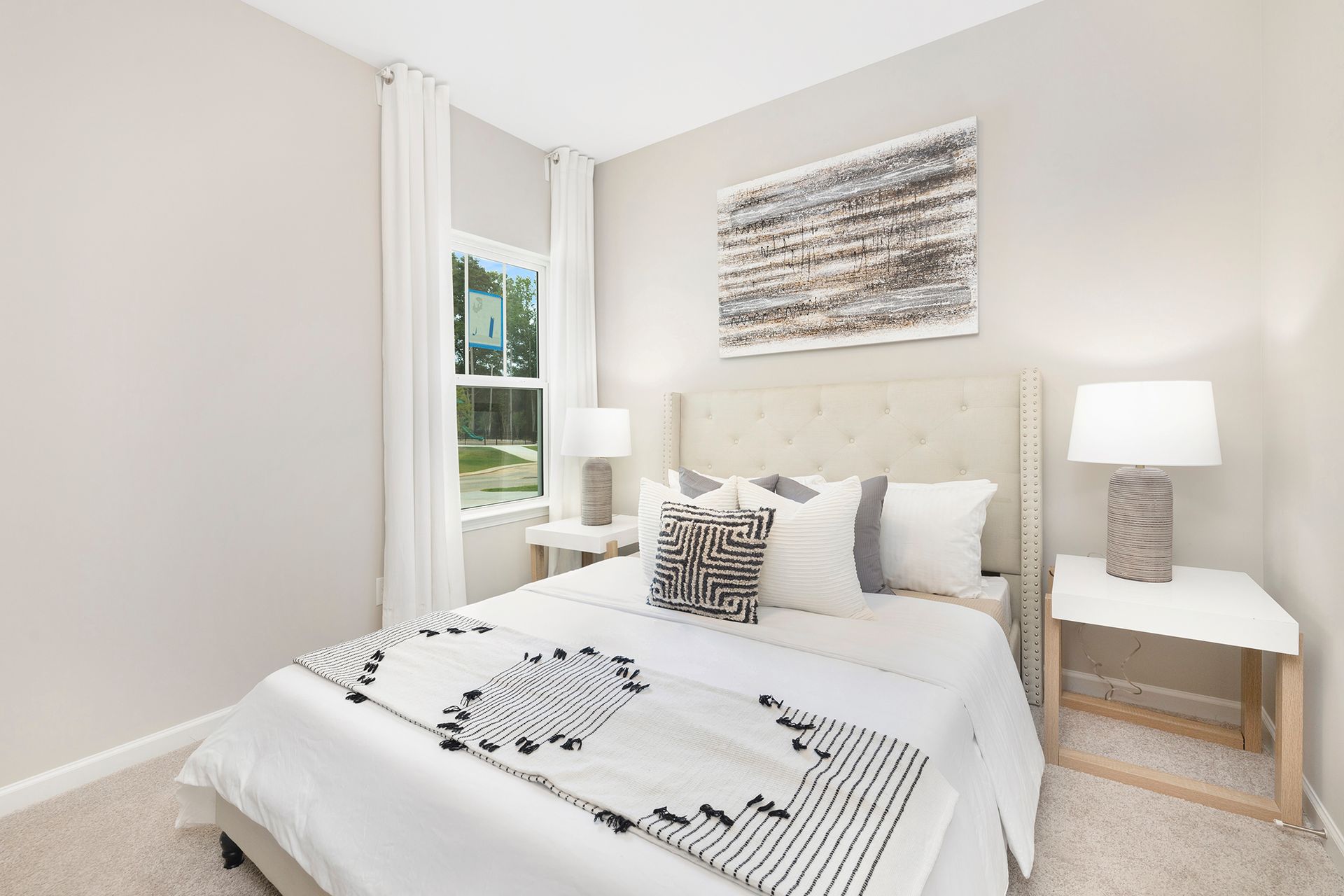 A bedroom with a bed , nightstand , lamps and a window.