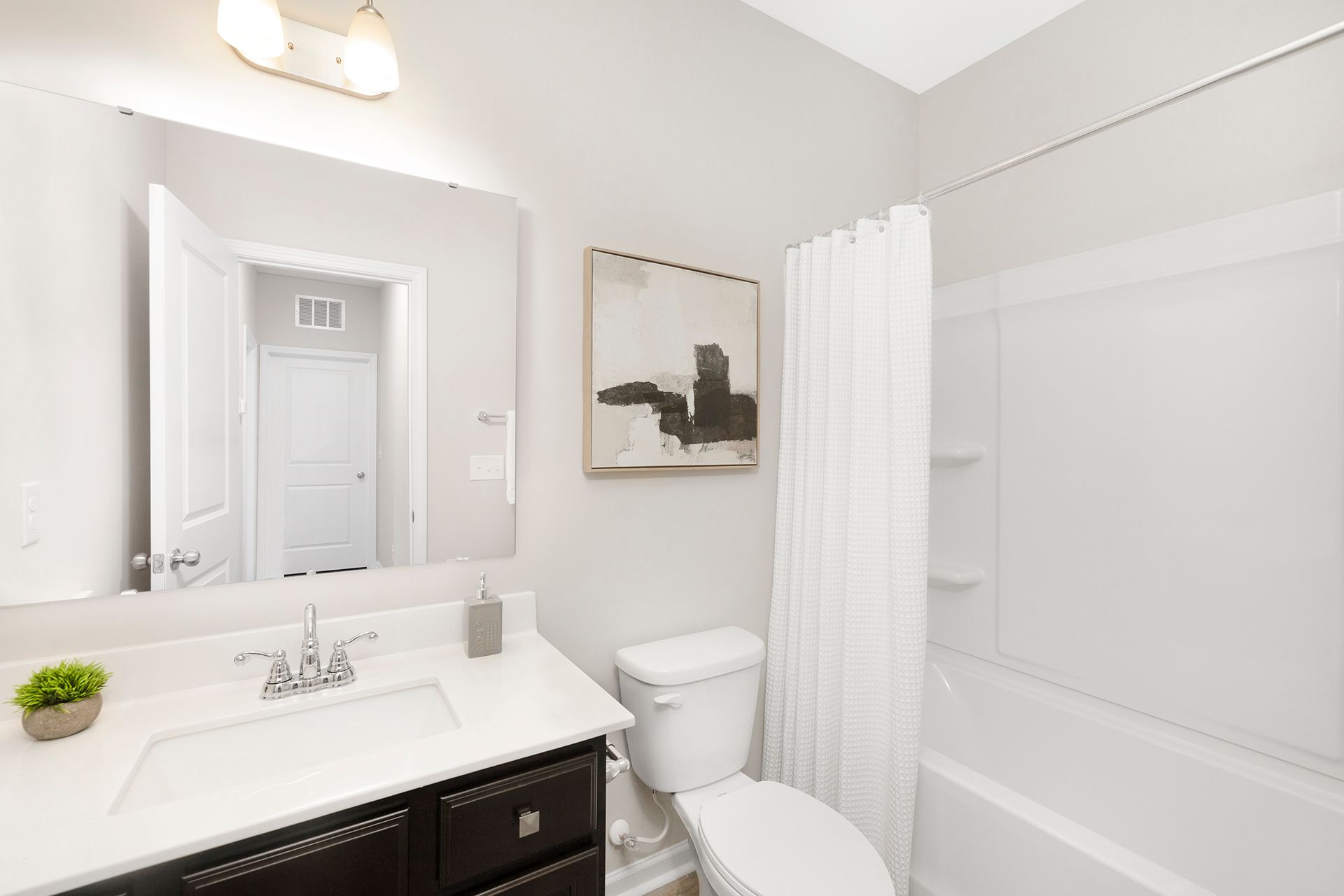 A bathroom with a toilet , sink , mirror and bathtub.