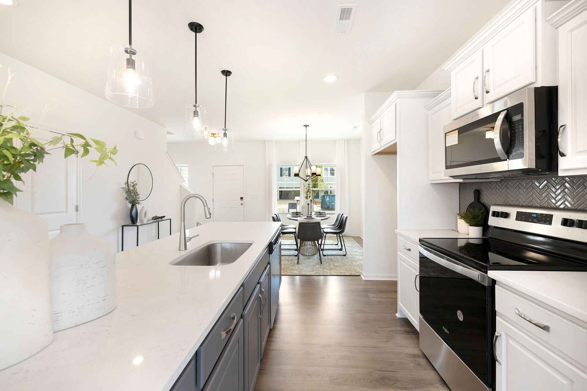 A kitchen with white cabinets , stainless steel appliances , a sink , and a microwave.