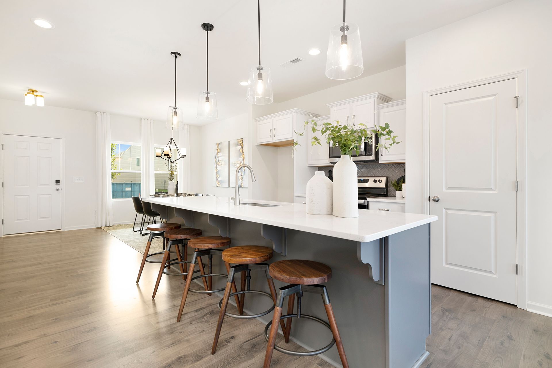 A kitchen with a long island and stools in a house.