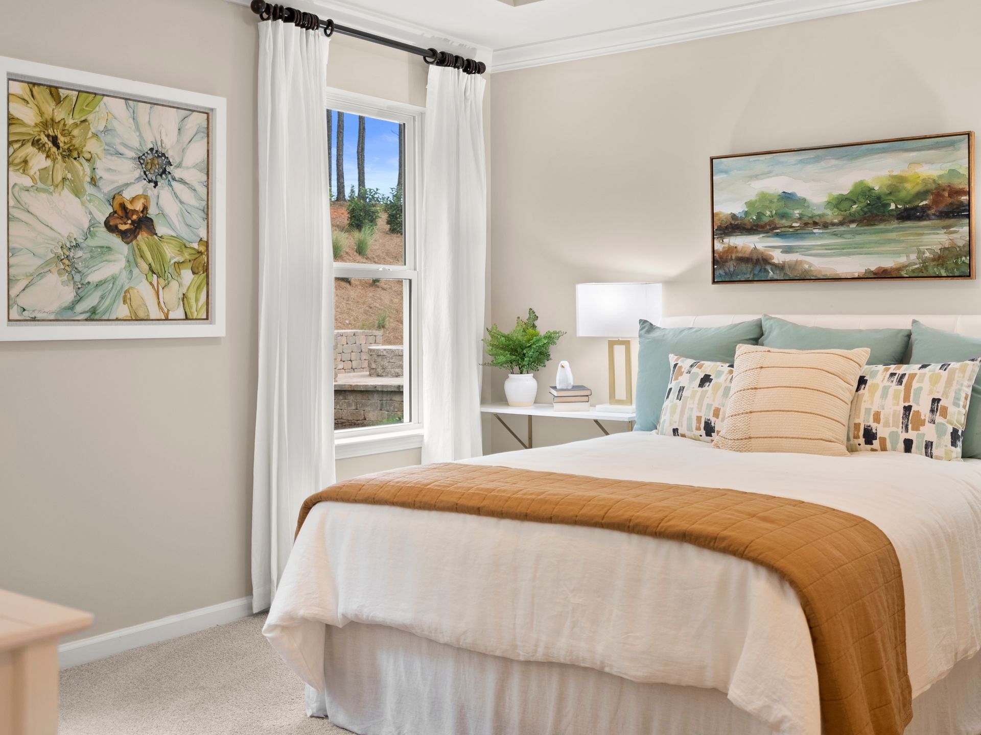 A bedroom with a bed , two paintings on the wall and a window.