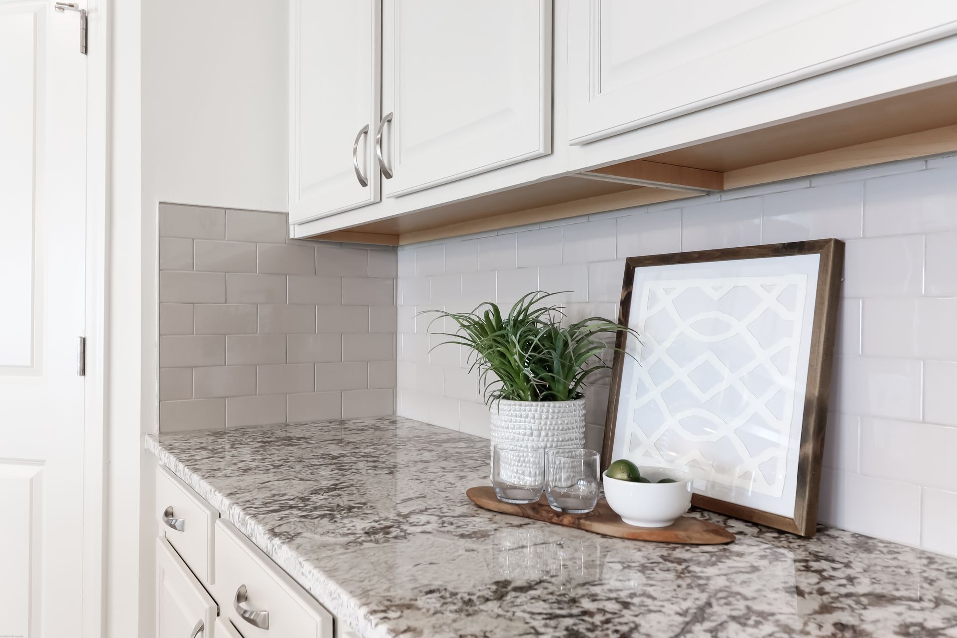 A kitchen counter with granite counter tops and white cabinets.