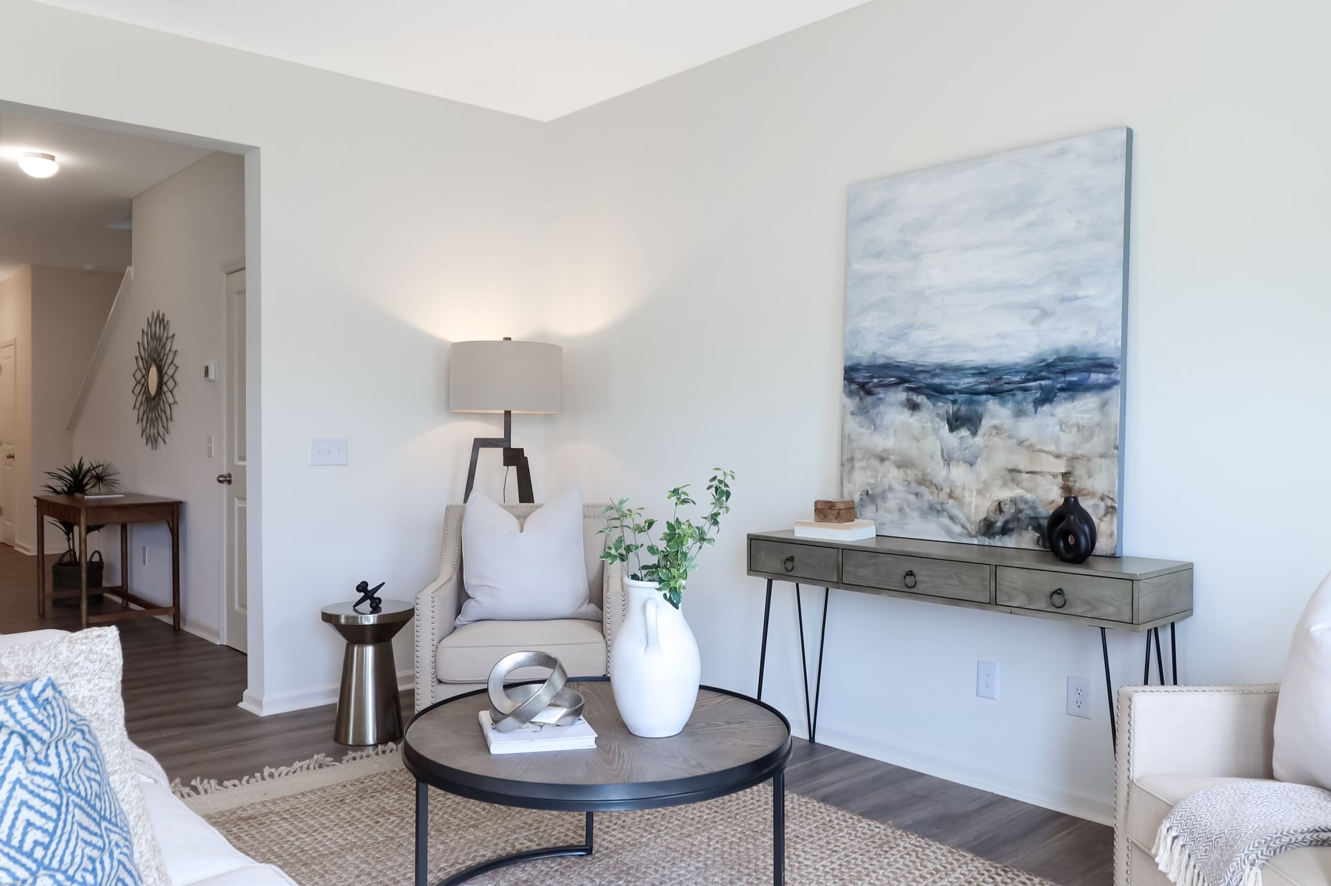 A living room with a table , chairs , and a painting on the wall.