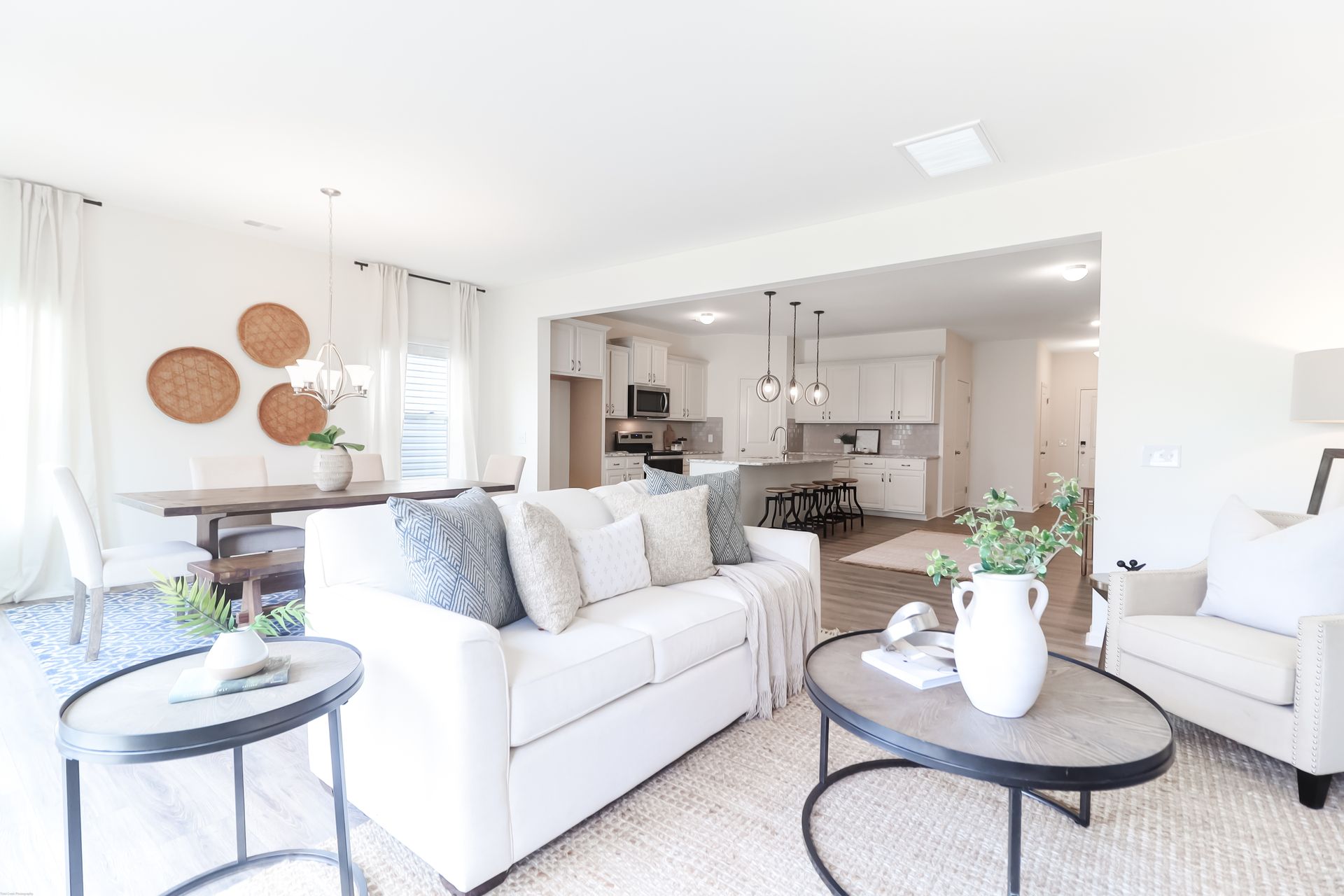 A living room with a white couch , two chairs , a coffee table and a table.
